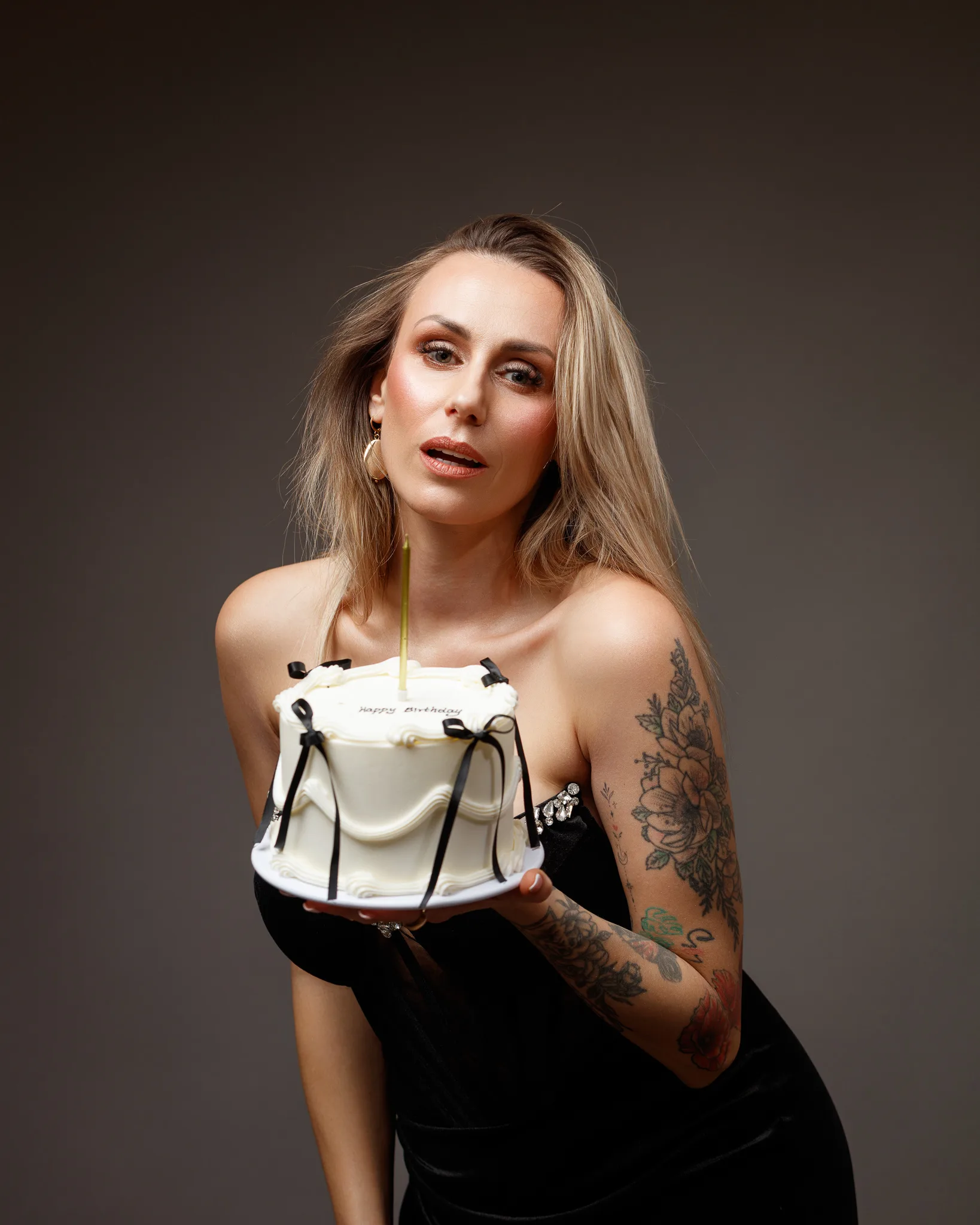 Woman holding birthday cake with single candle.