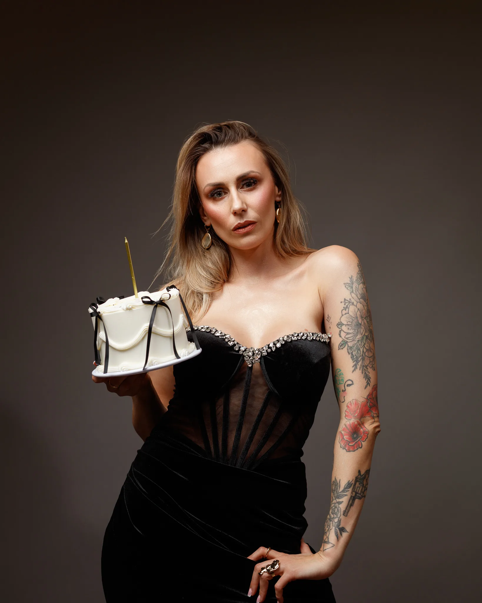Woman holding a decorated cake, wearing elegant dress.