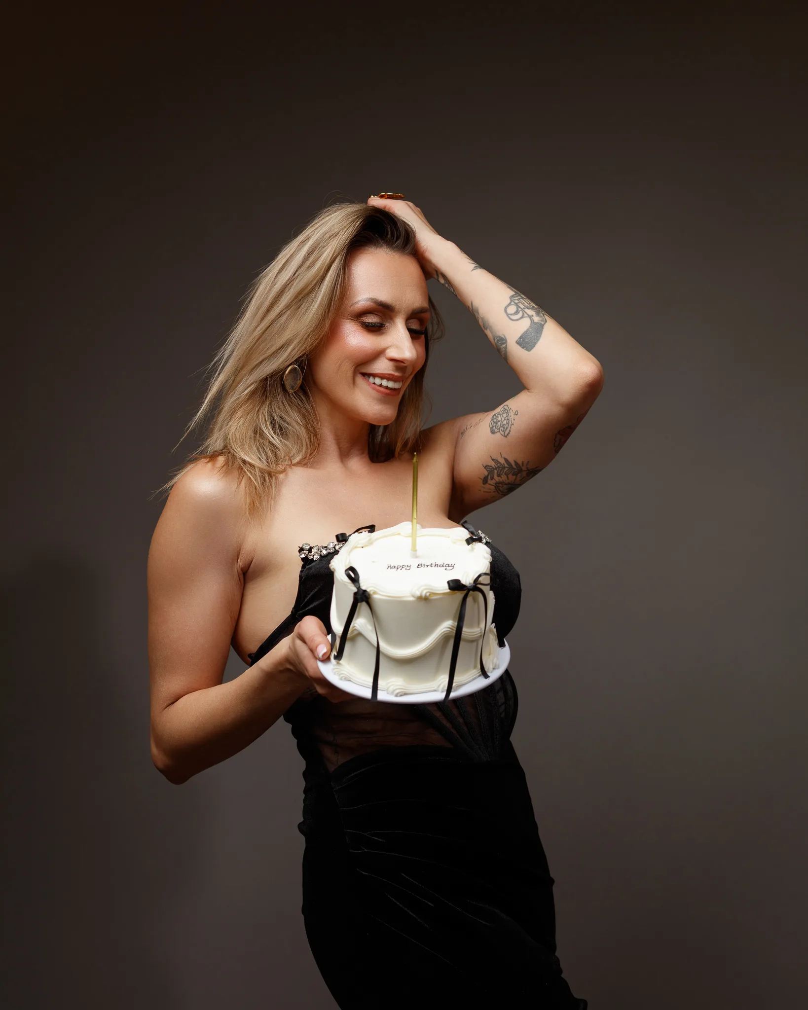 Smiling person holding birthday cake with candle.