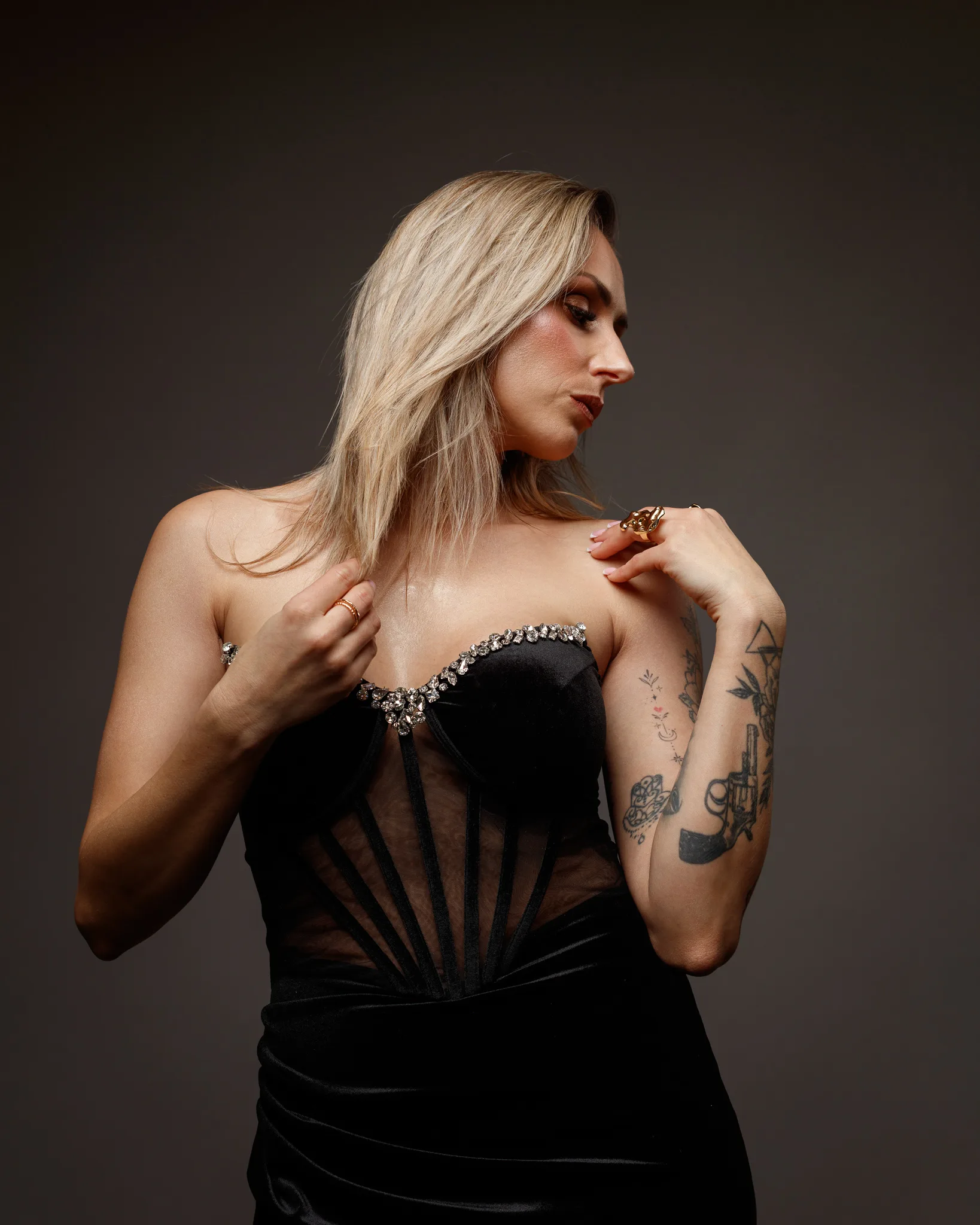Woman in black dress with tattoos posing elegantly.