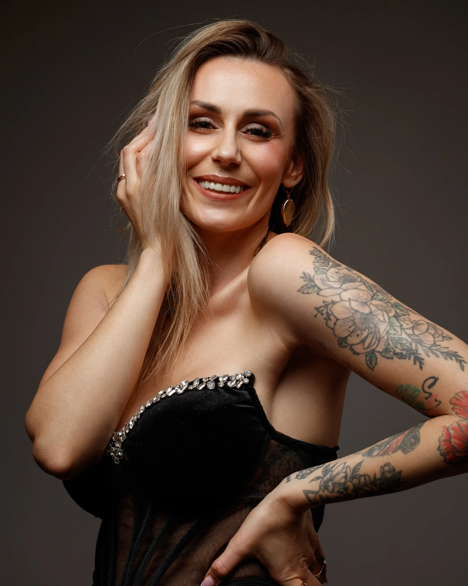 Smiling woman with floral tattoos and elegant dress.