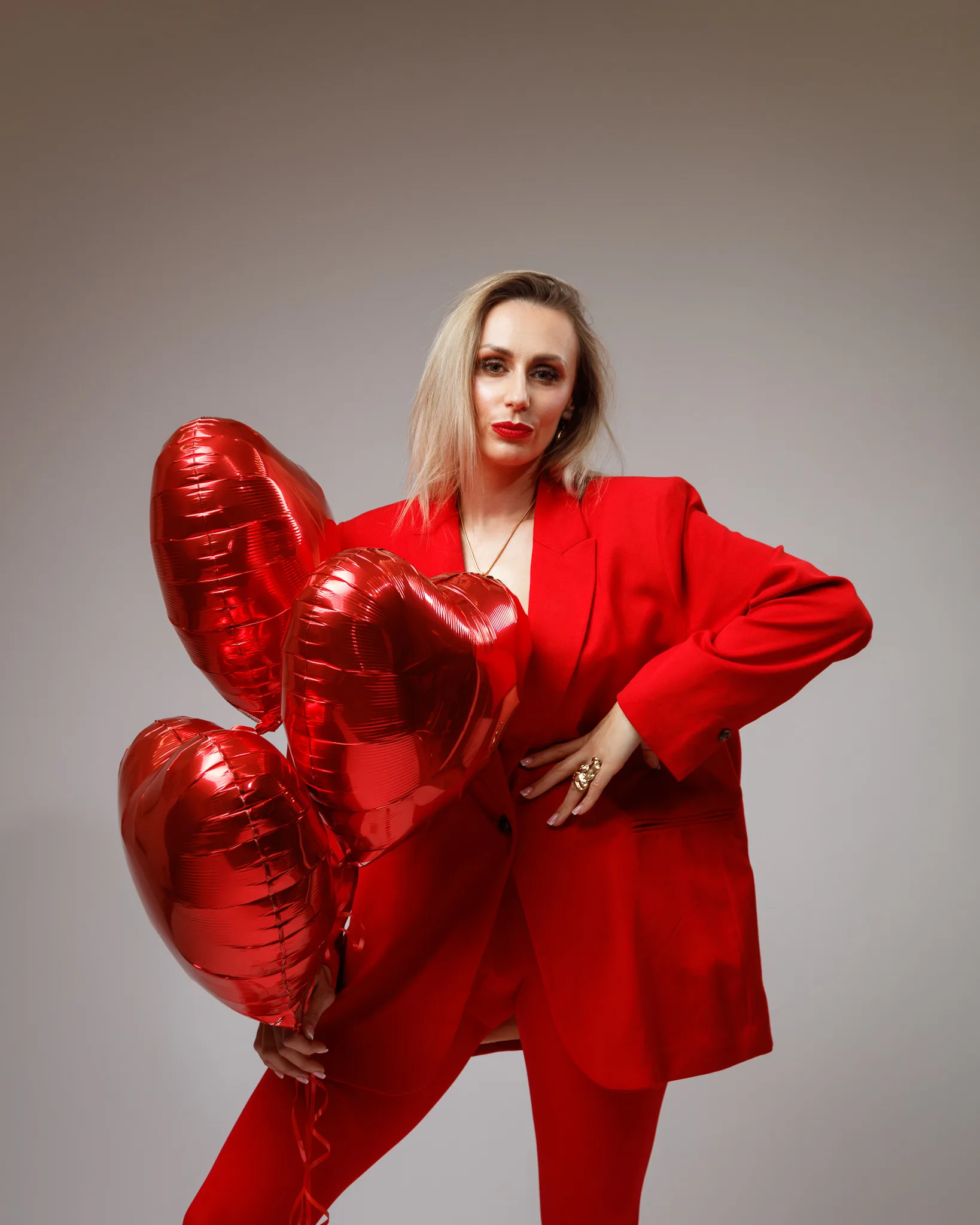 Person in red outfit with heart balloons.