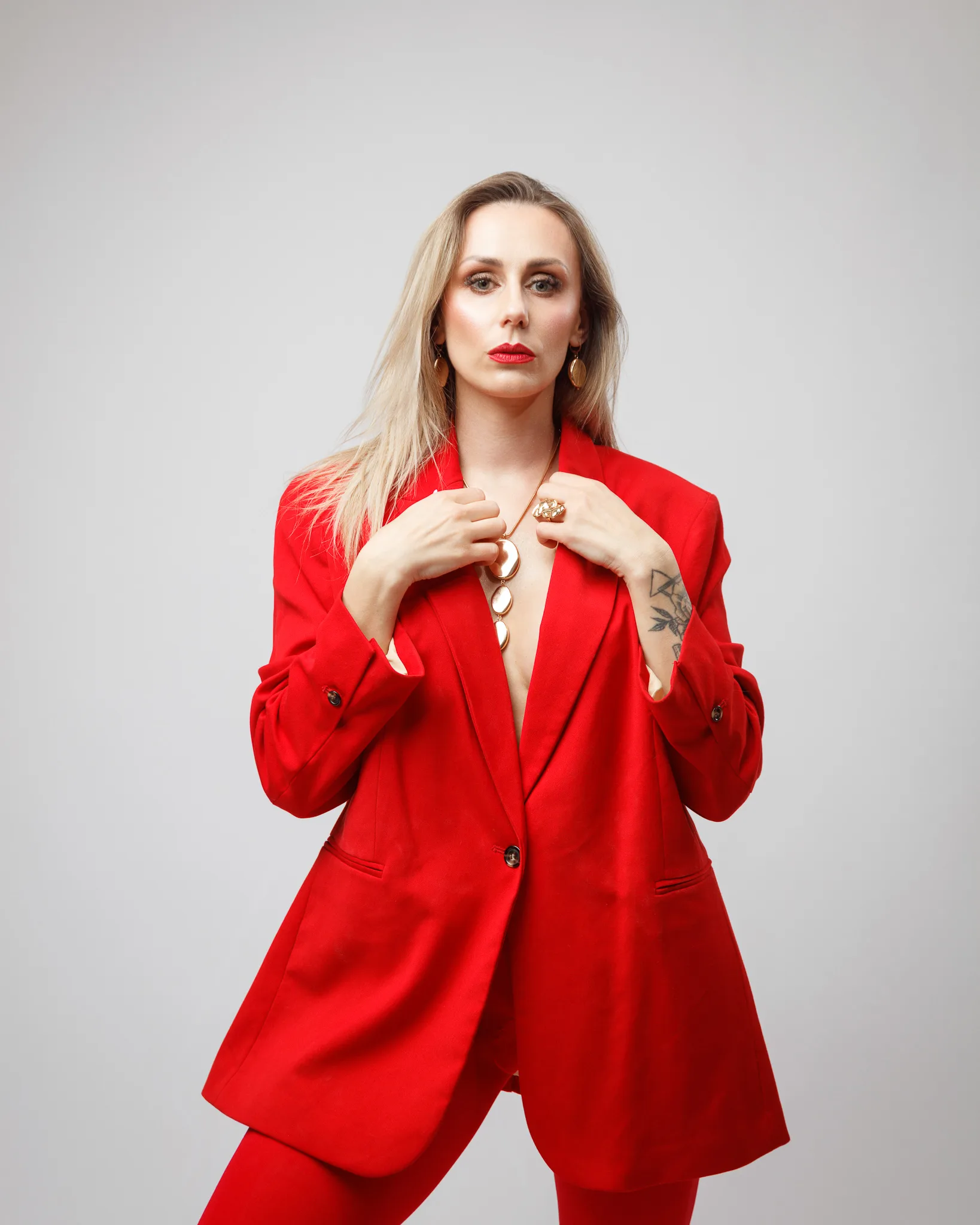 Person in stylish red suit posing confidently.