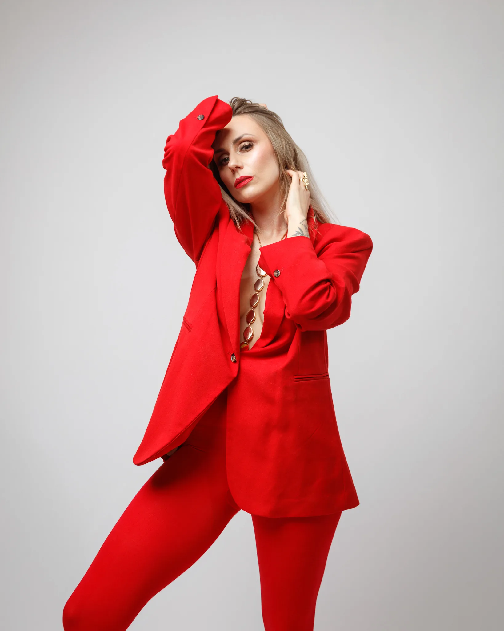 Woman in vibrant red suit posing confidently.