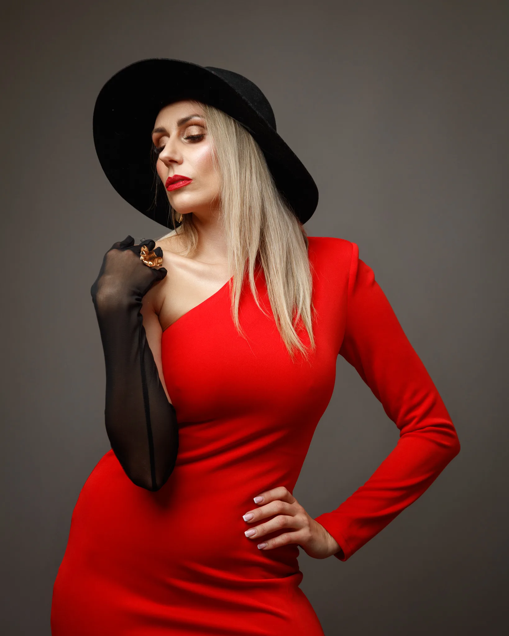 Fashionable woman in red dress and hat posing.