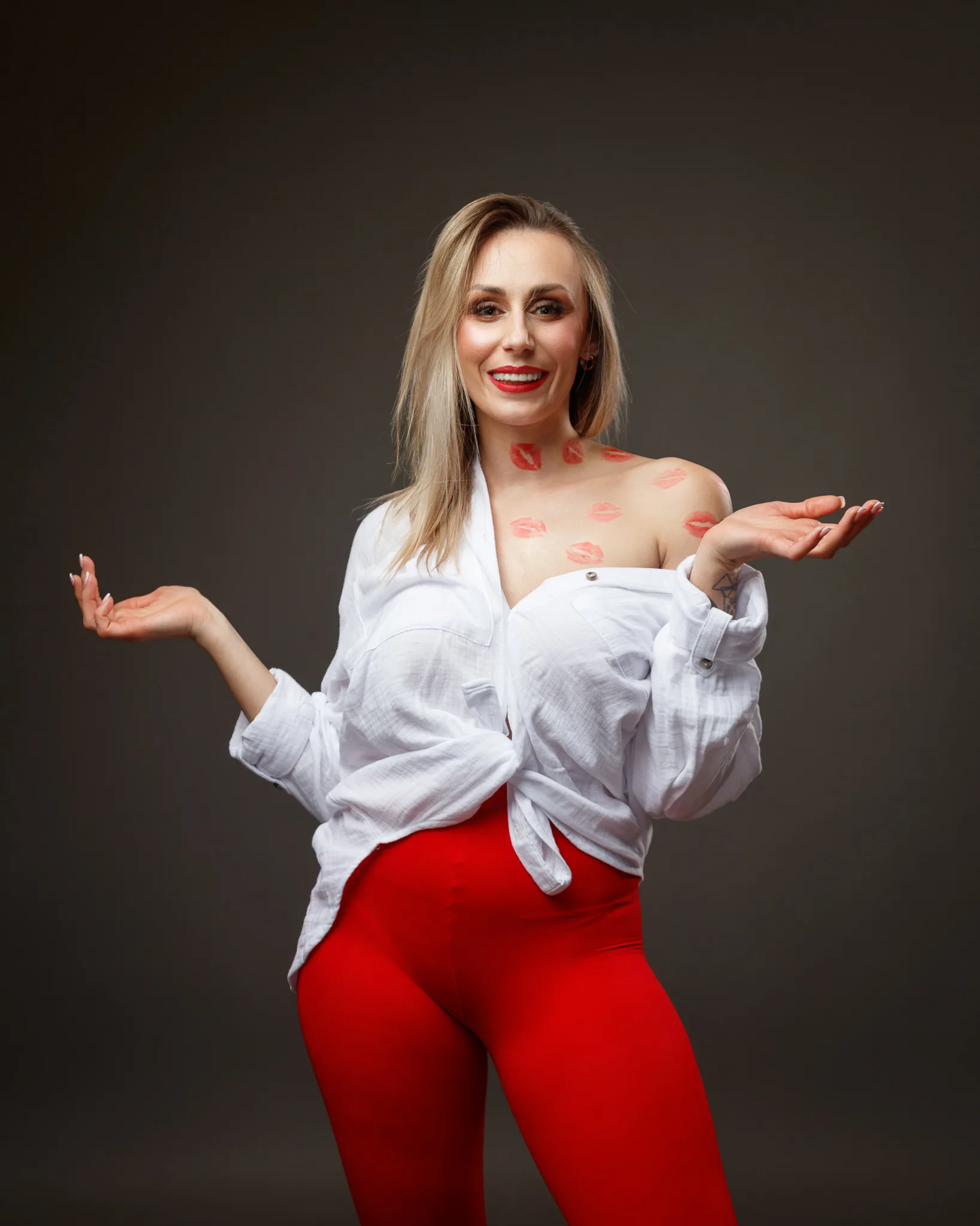 Smiling woman in red pants, lipstick marks on skin.