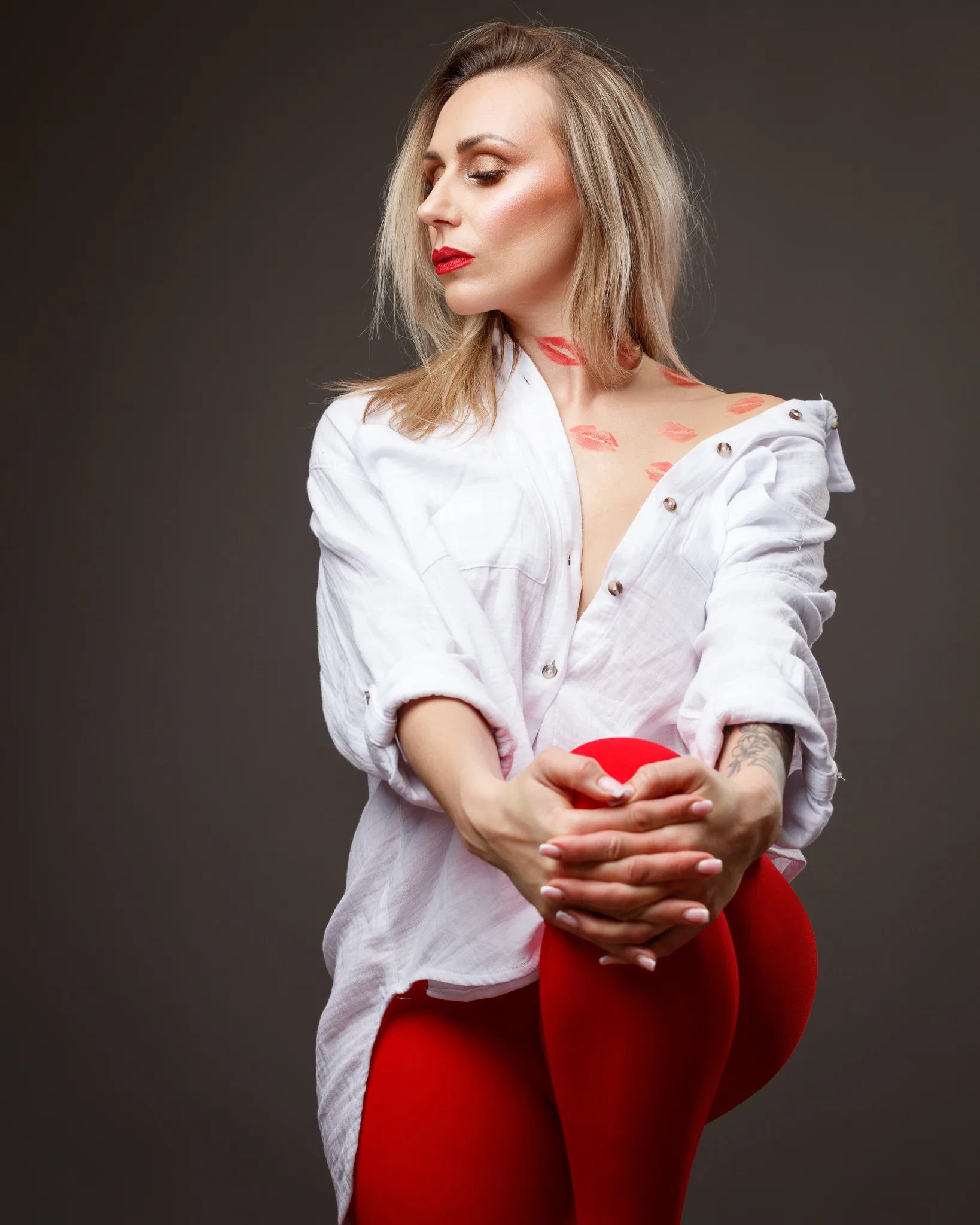 Woman in white shirt and red leggings posing confidently.