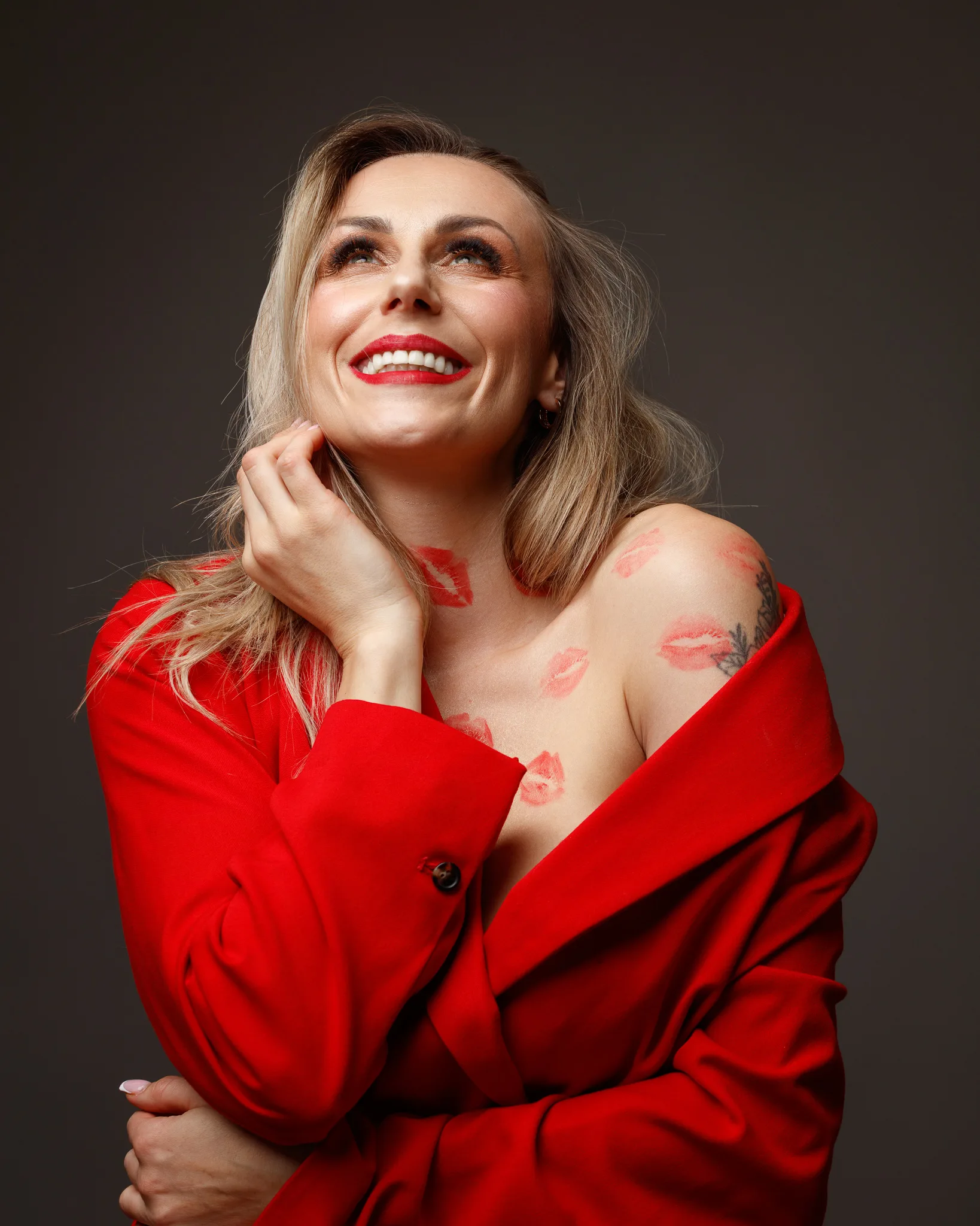 Smiling woman with lipstick marks in red coat.