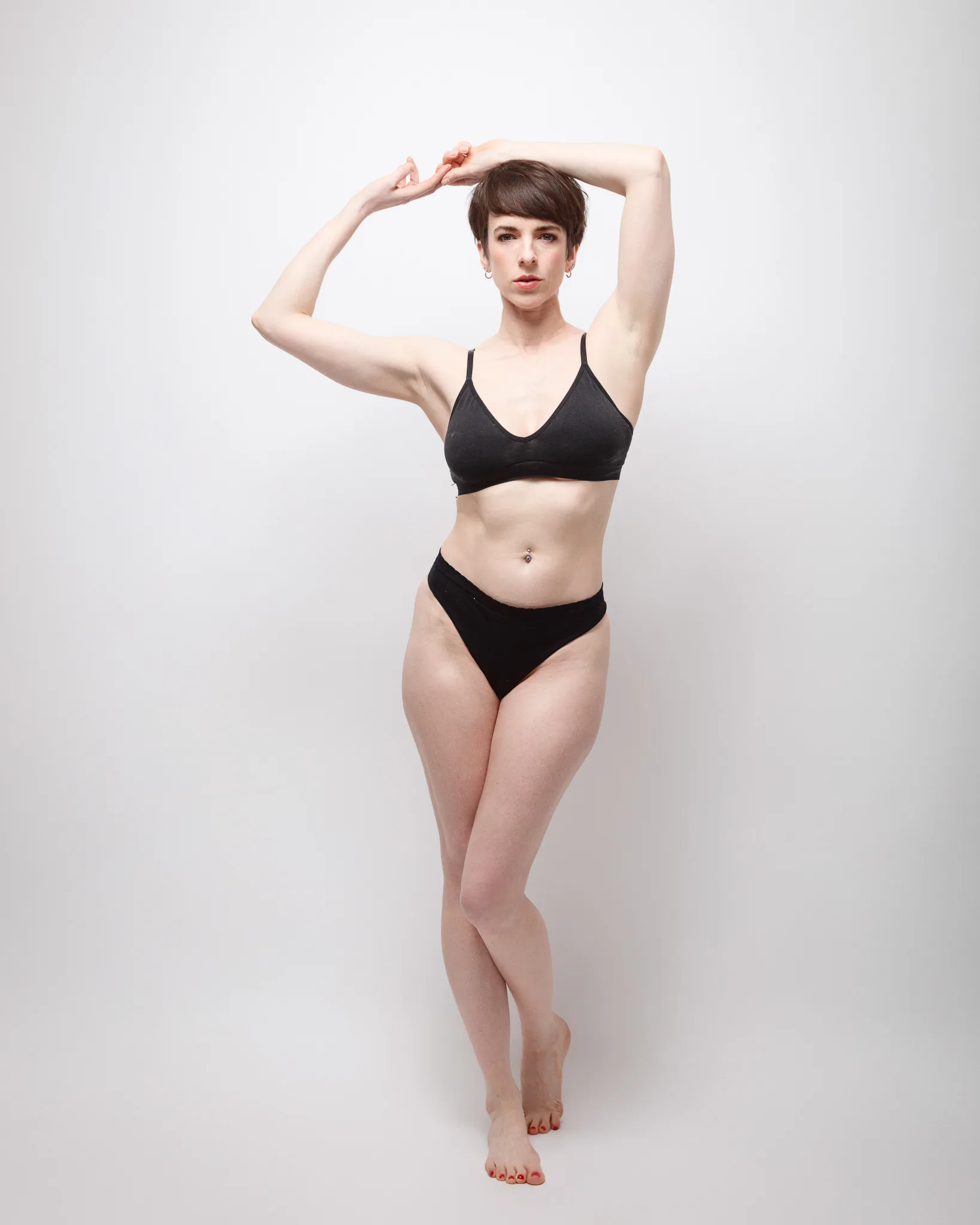 Person posing in black underwear against white background.