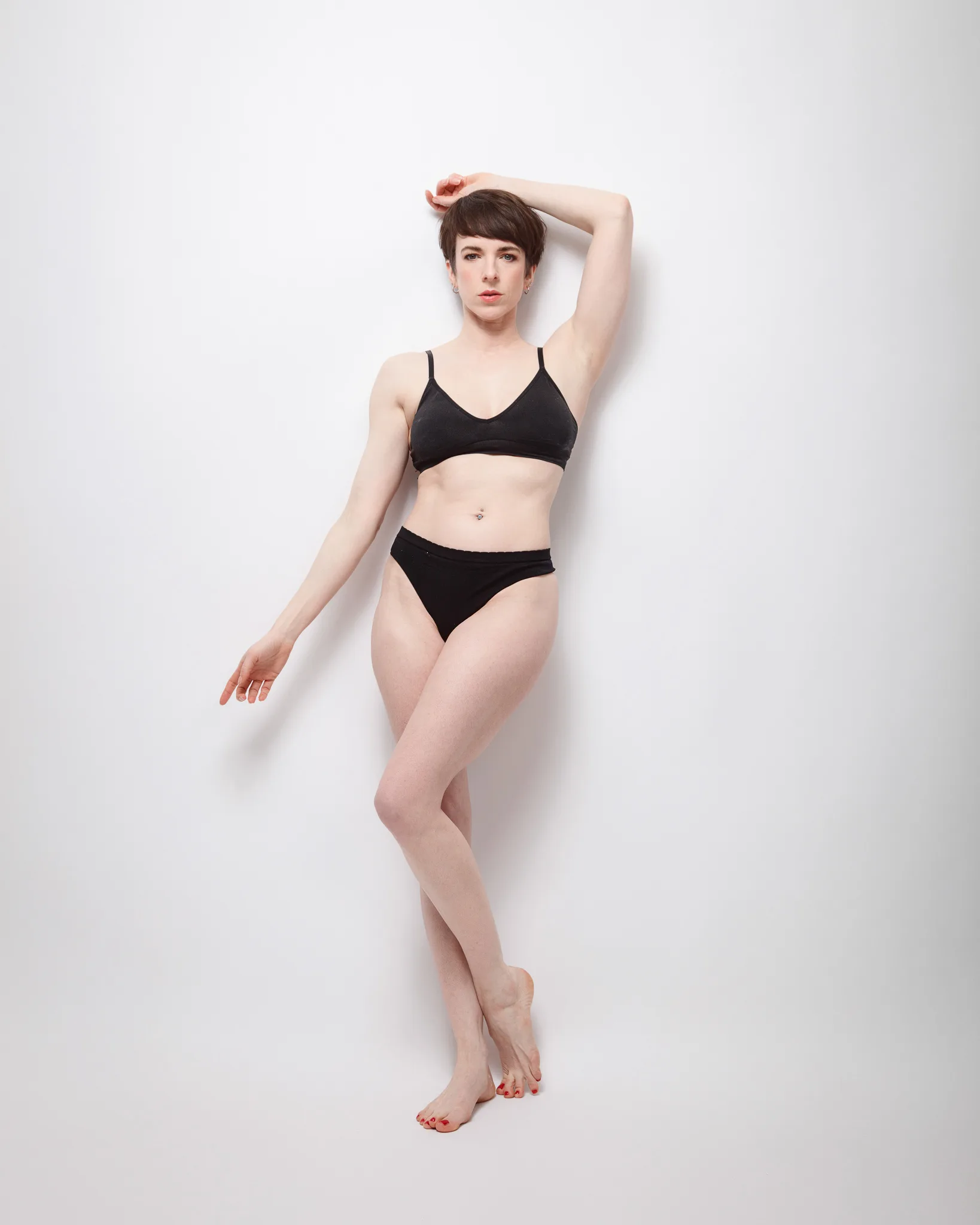 Person posing in black underwear against white background.