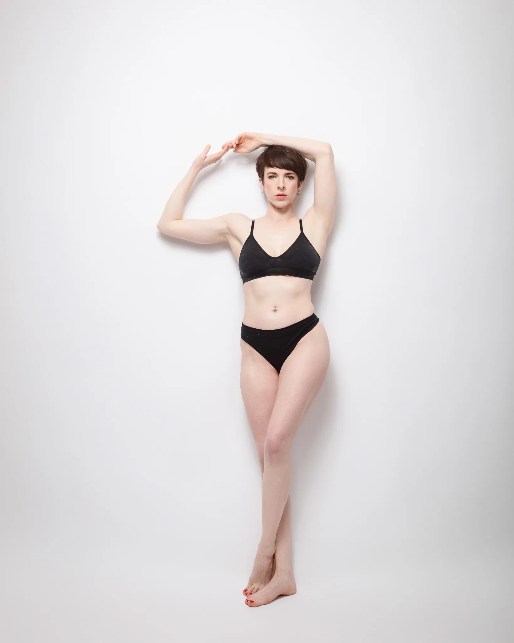 Person posing in black underwear against white background.