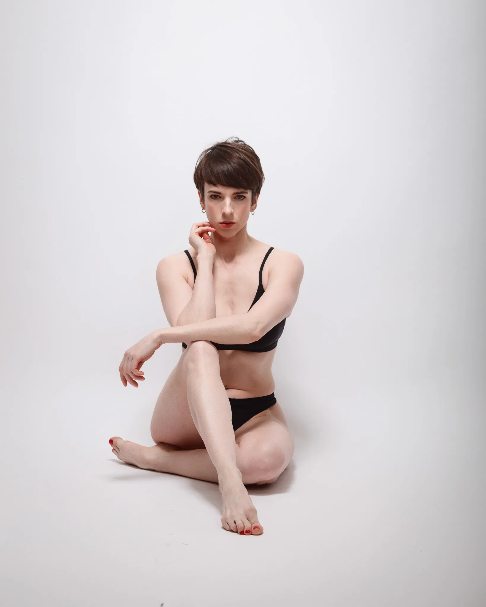 Person in black lingerie sitting on floor.