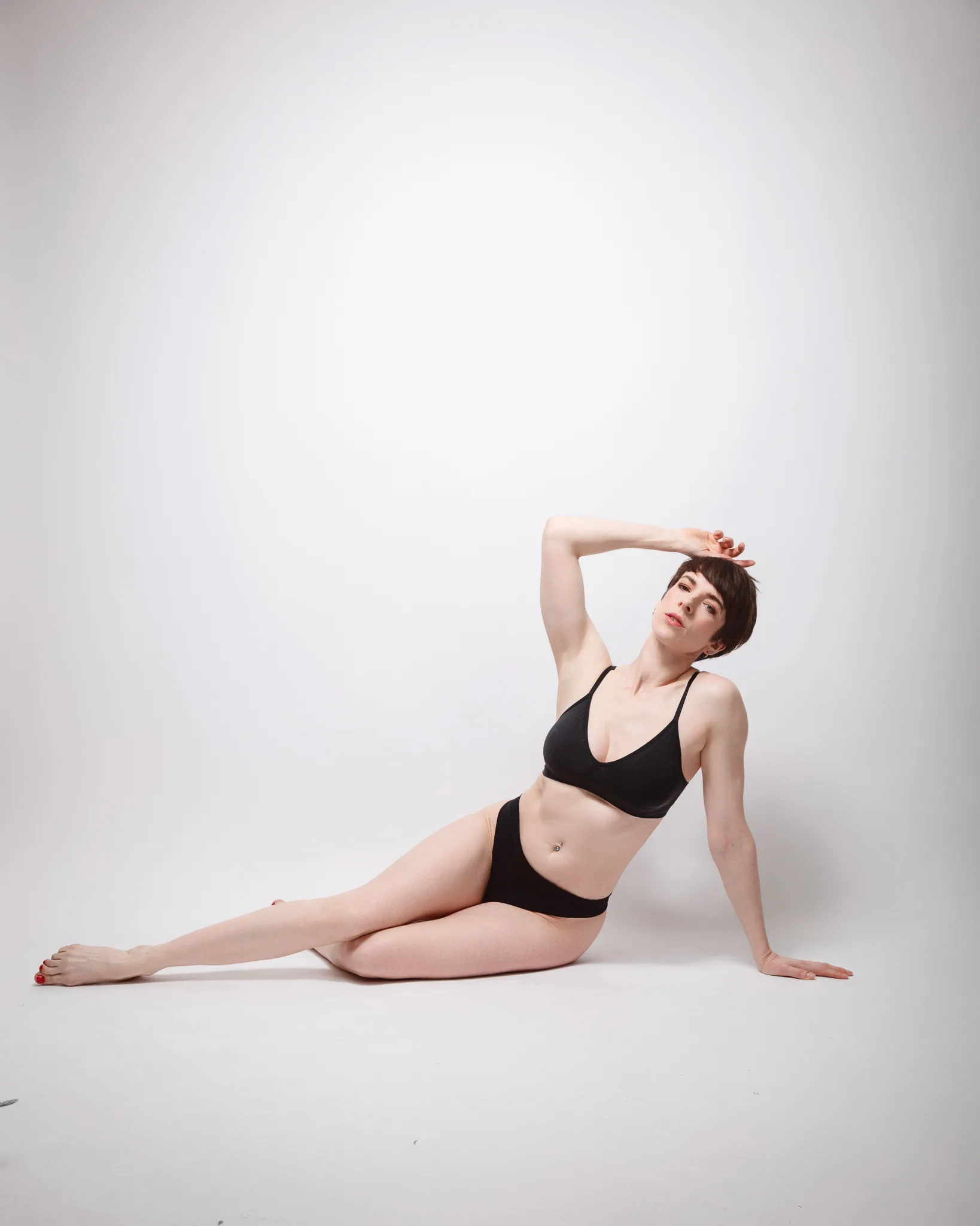 Person in black lingerie posing on white background.
