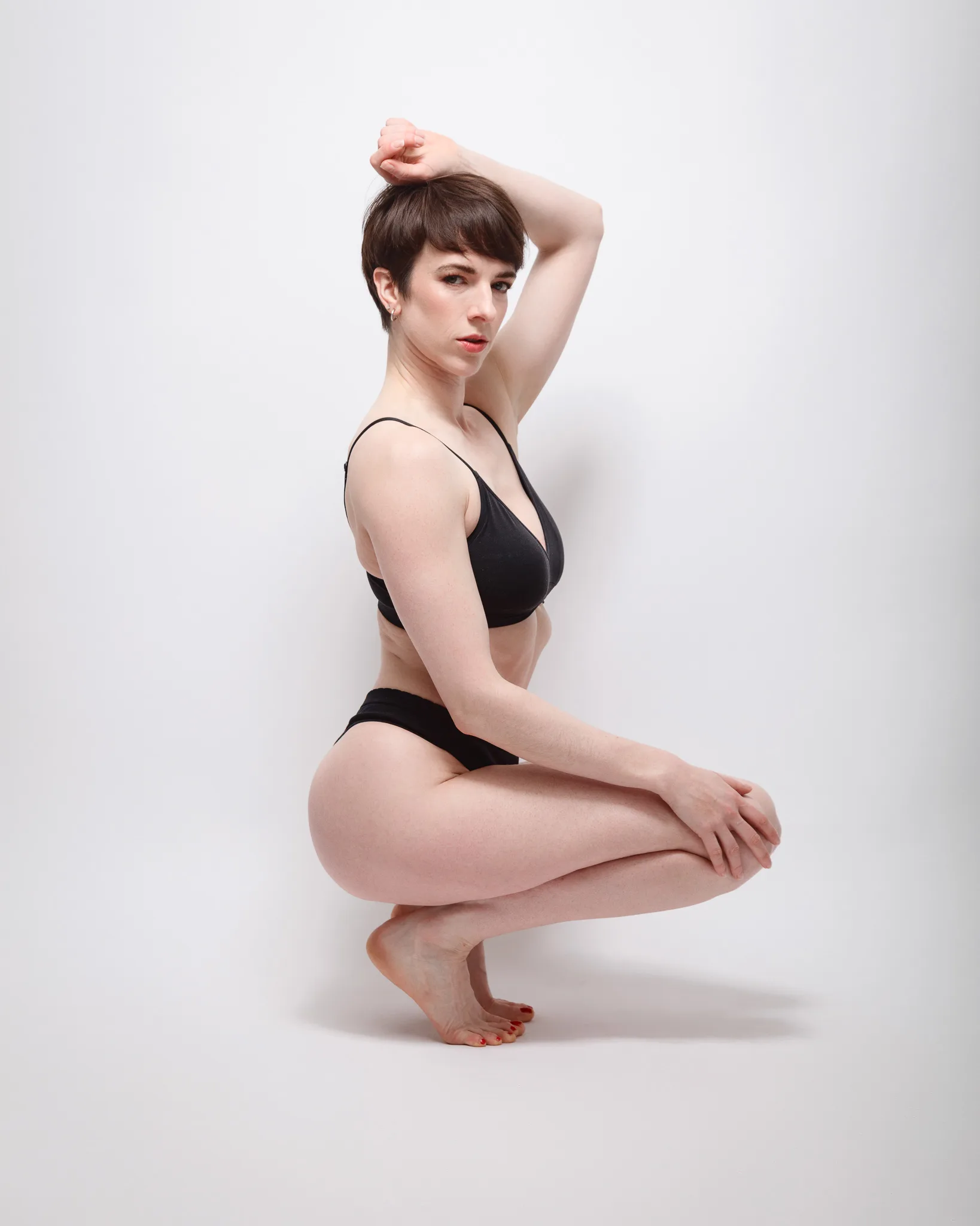 Person posing in black underwear against white background.