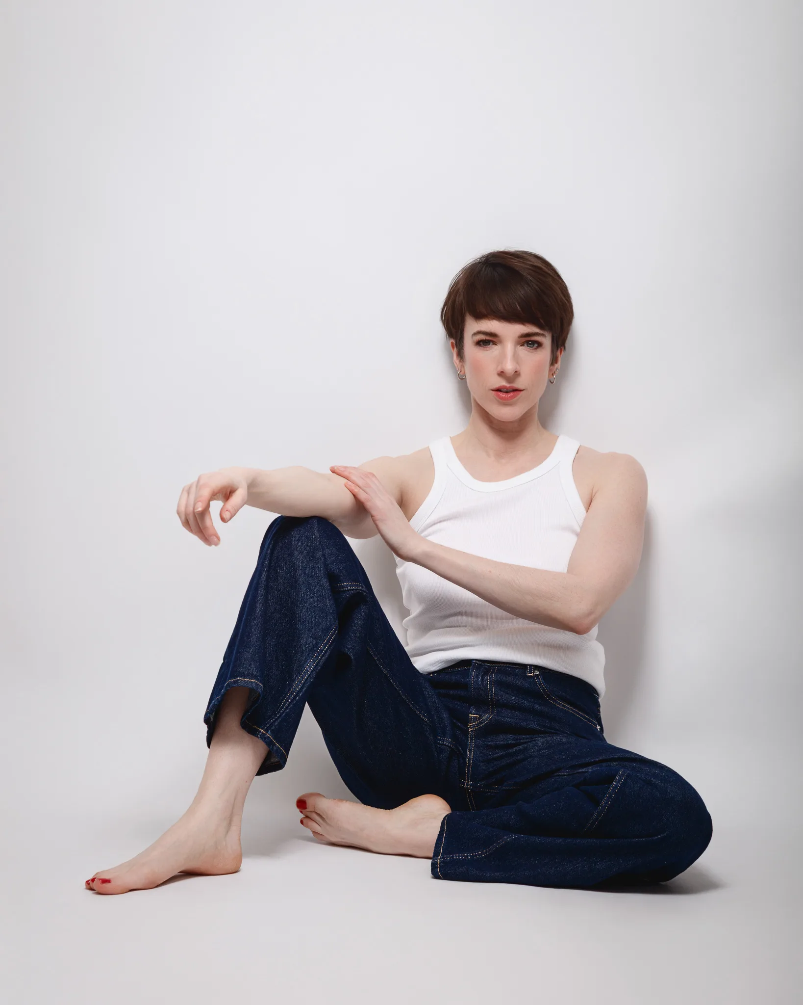 Person sitting cross-legged in white tank top.