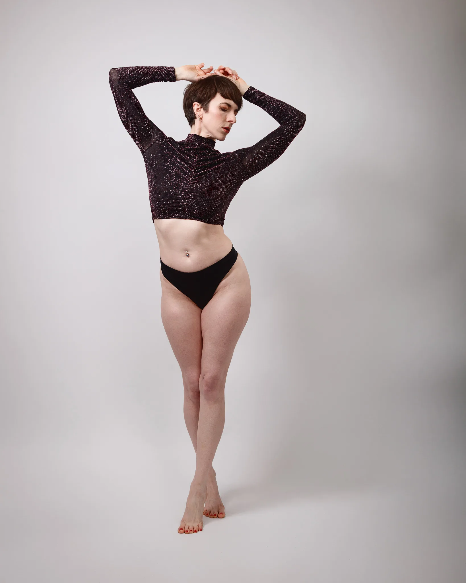 Person posing in stylish outfit against grey background.