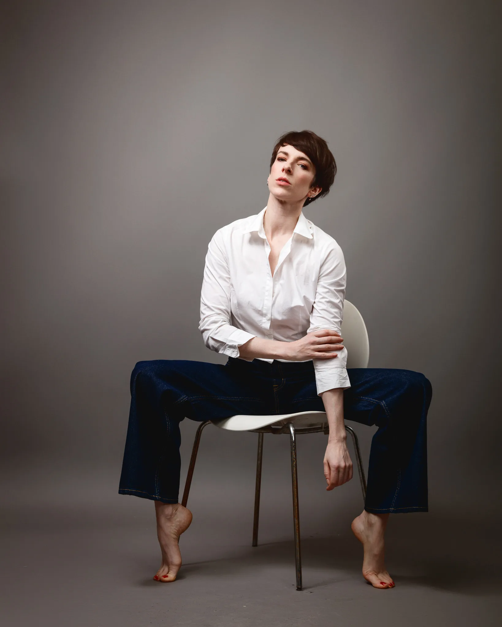Person seated on chair, posing confidently.