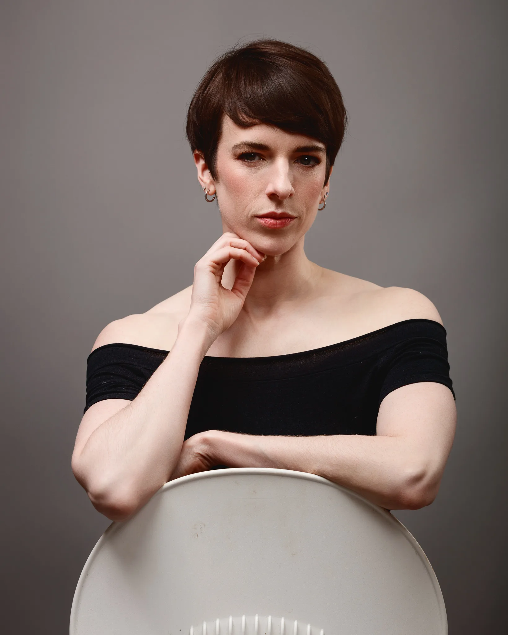 Person posing with short hair and off-shoulder top.