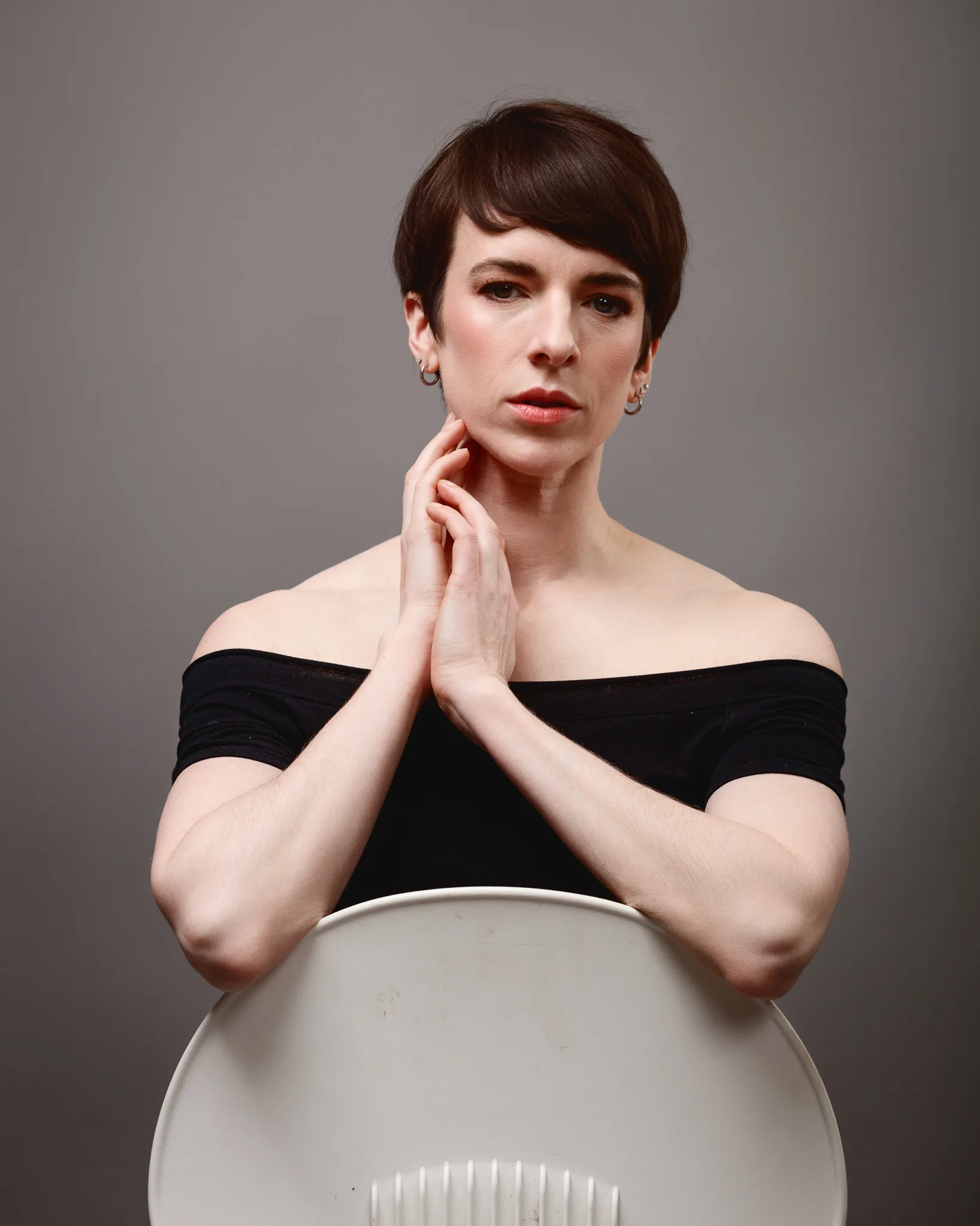 Person posing behind chair with thoughtful expression.