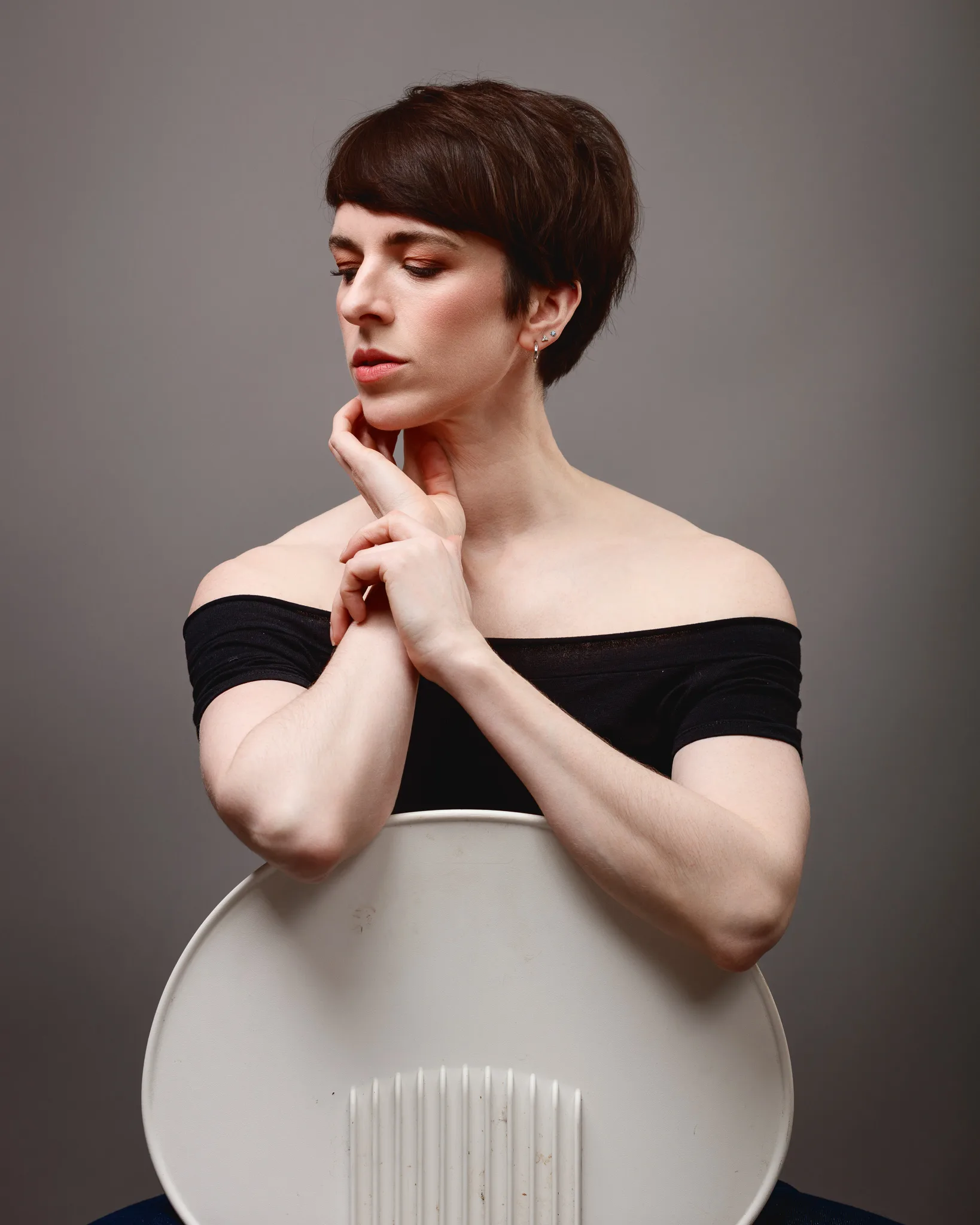 Person posing elegantly behind chair.