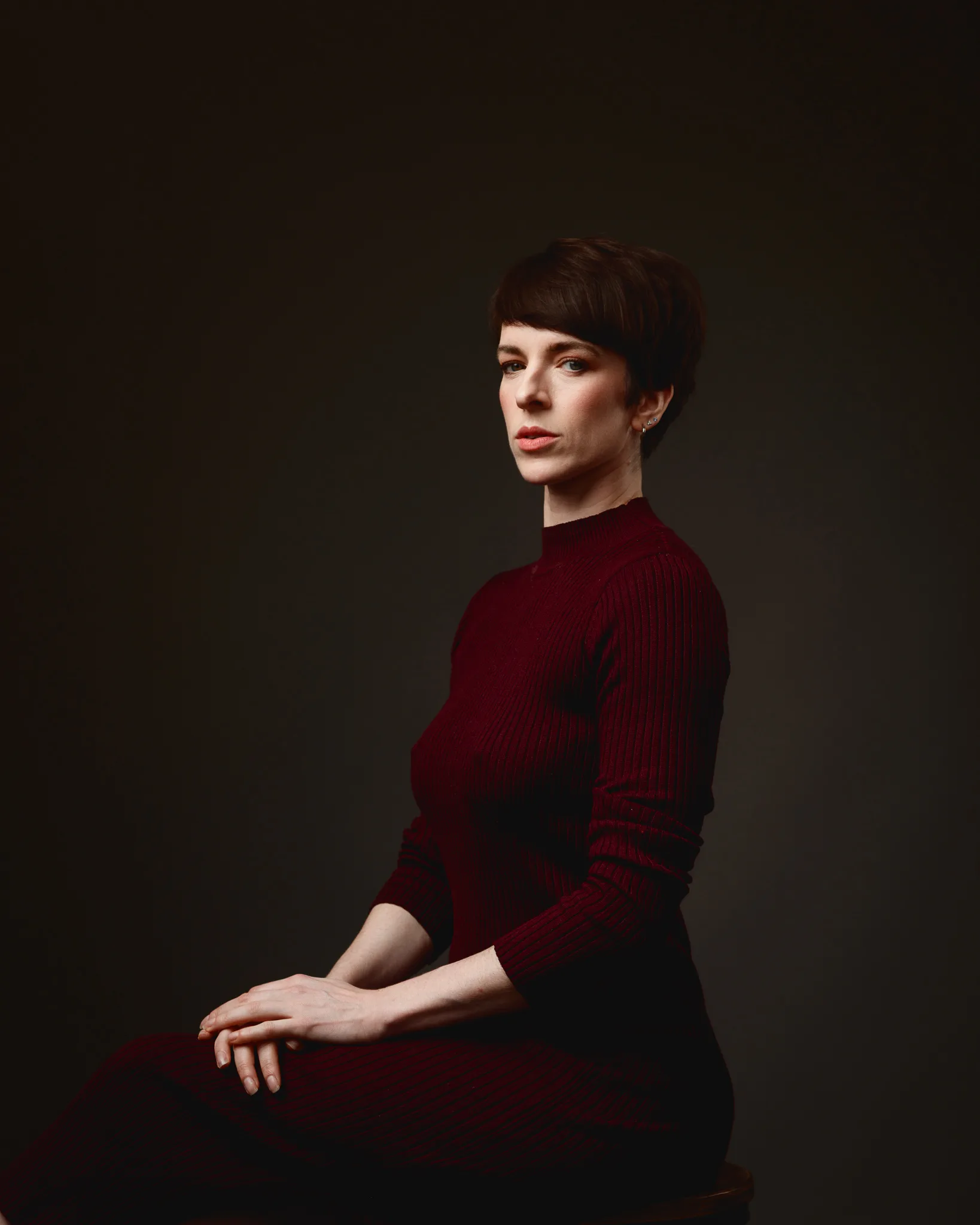 Person in burgundy dress against dark background