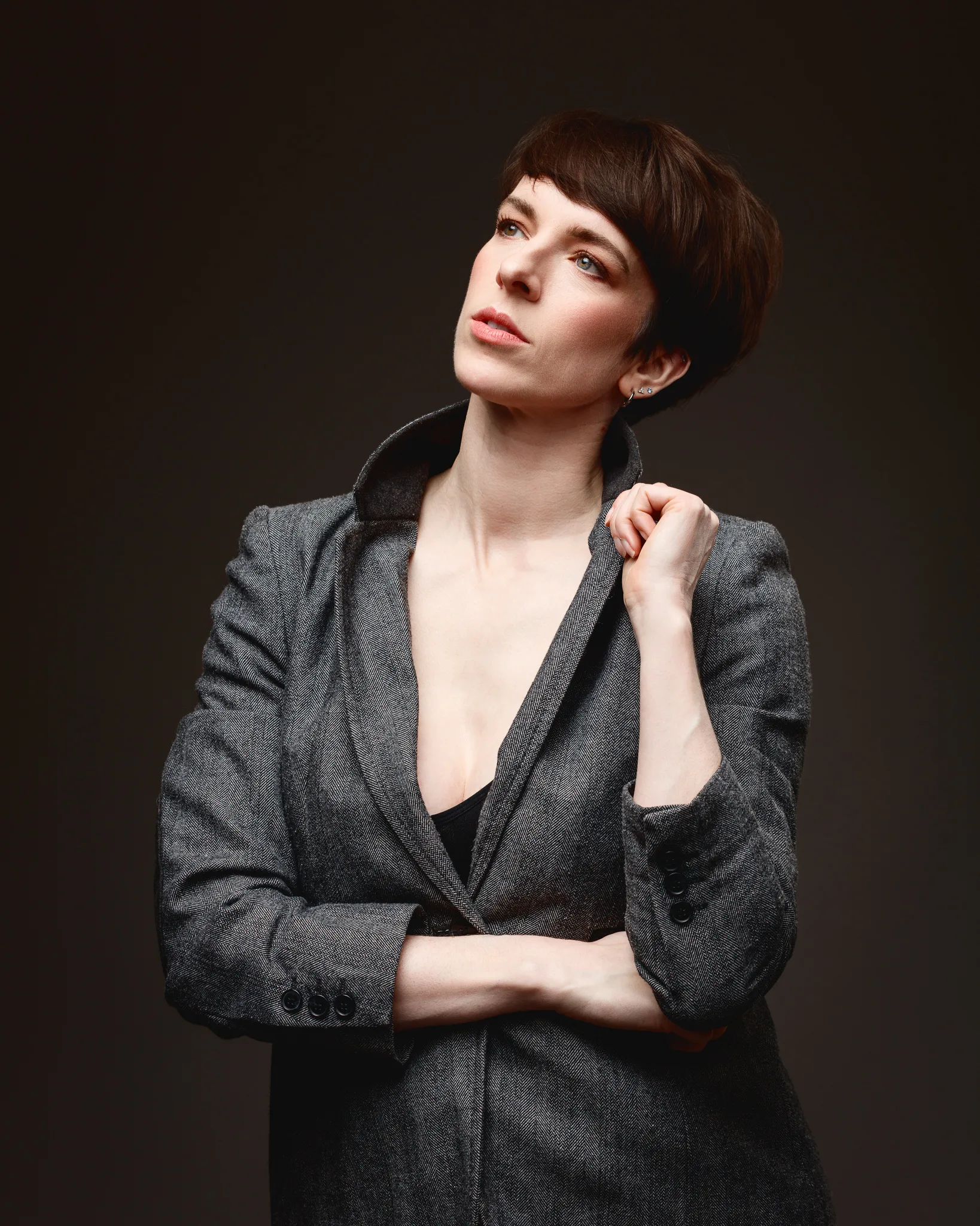 Person in grey jacket looking upwards thoughtfully.