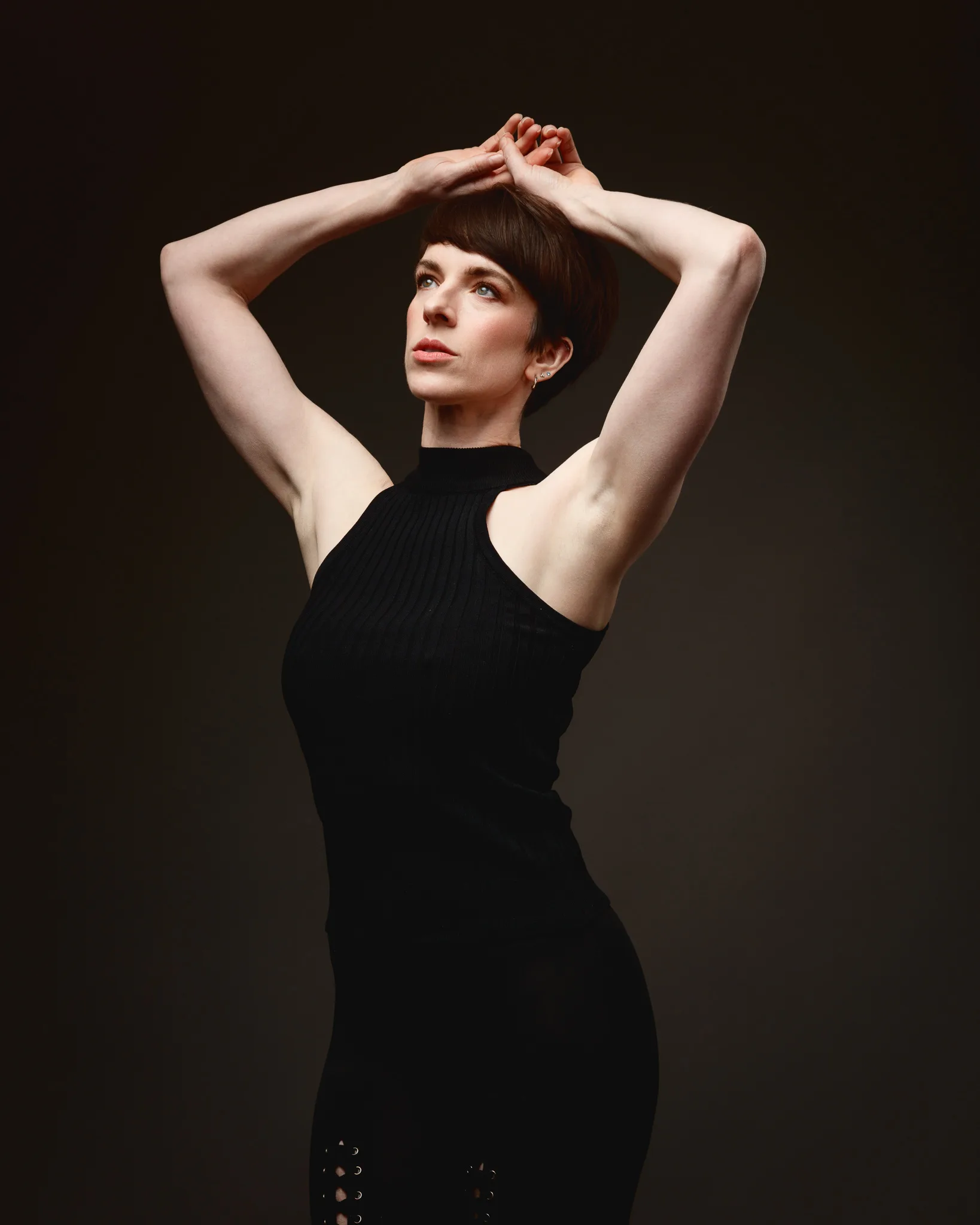 Woman posing with arms raised, wearing black.