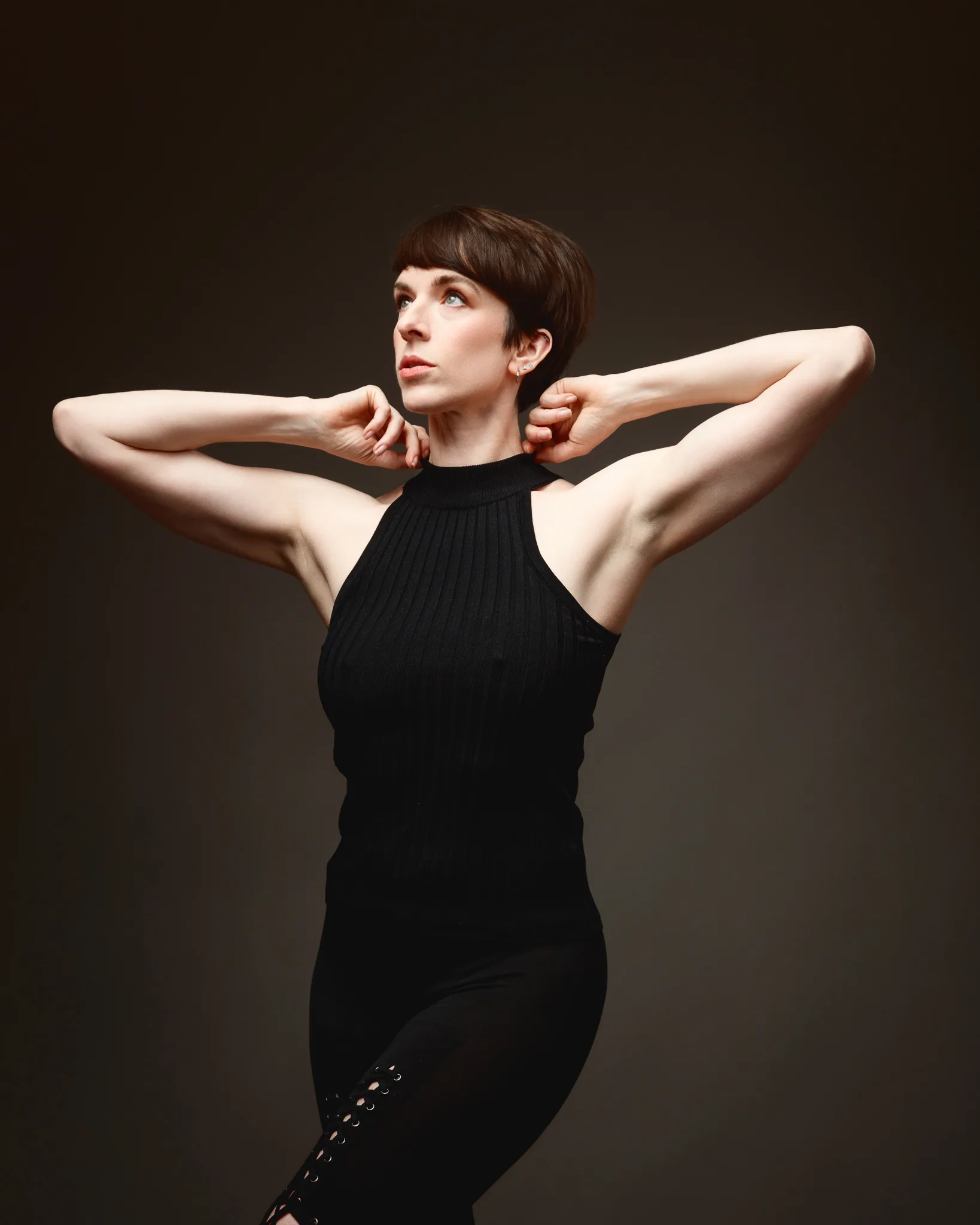 Woman posing in black sleeveless outfit, artistic lighting.