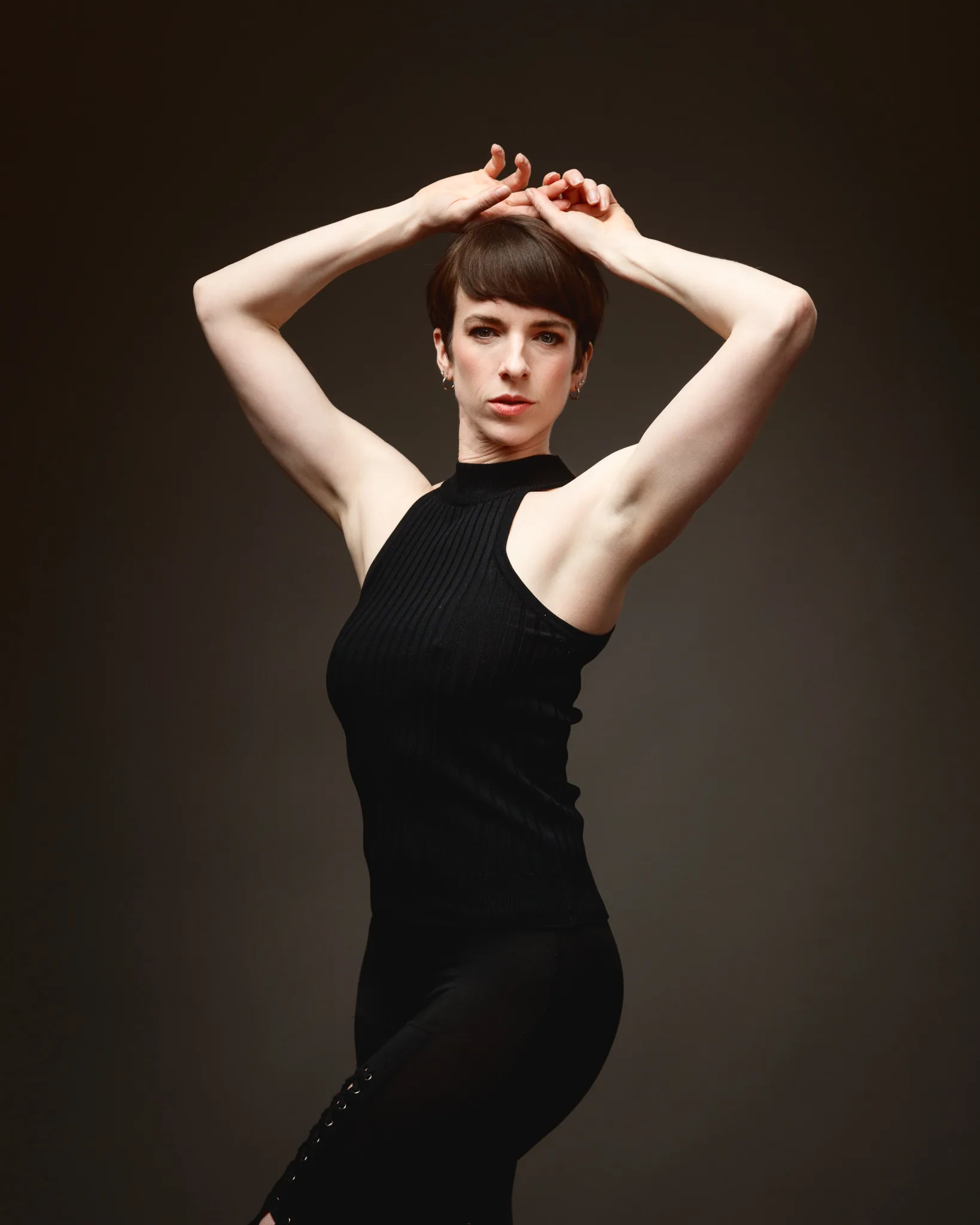 Person posing gracefully in black clothing.