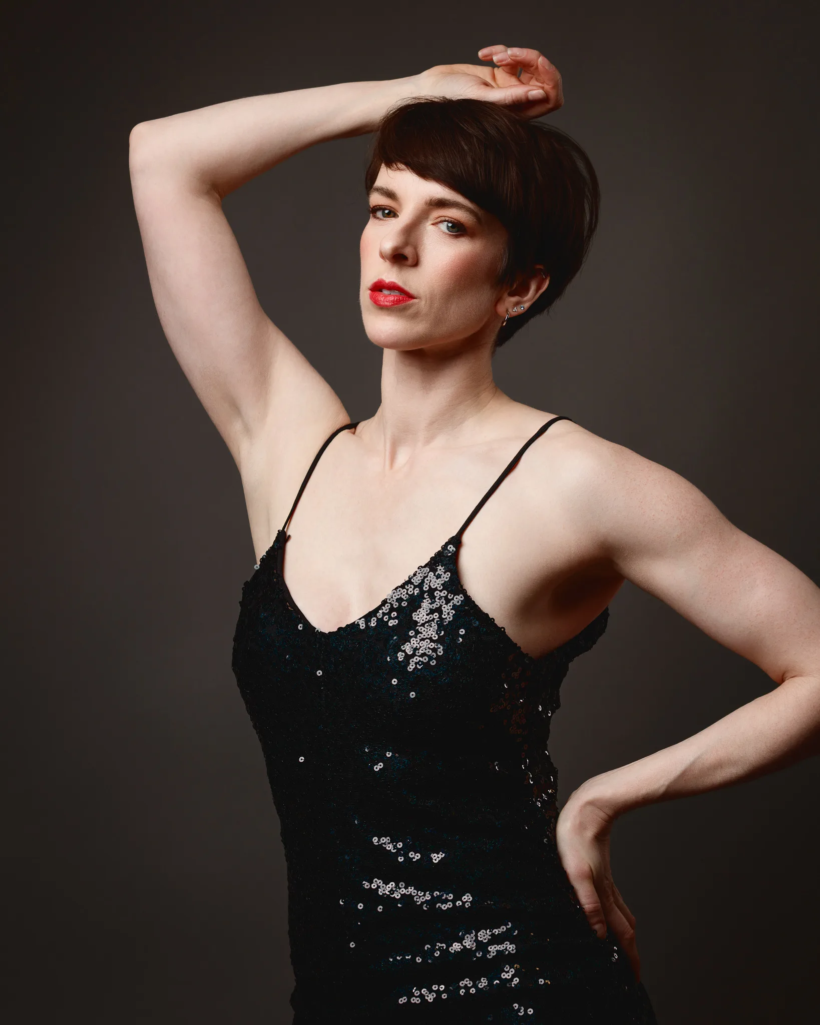 Person in black sequined dress posing elegantly.