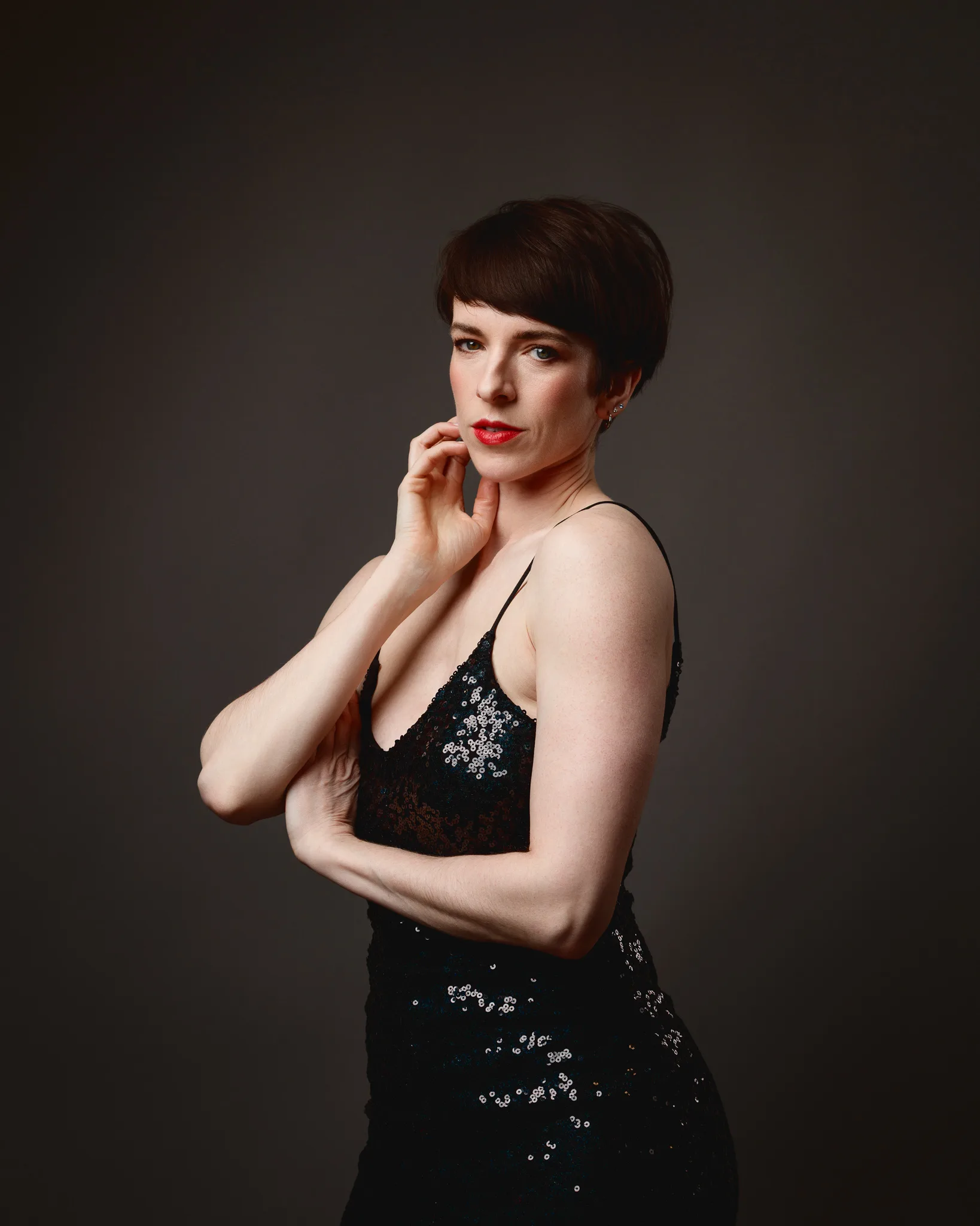 Woman in black sequined dress posing elegantly.