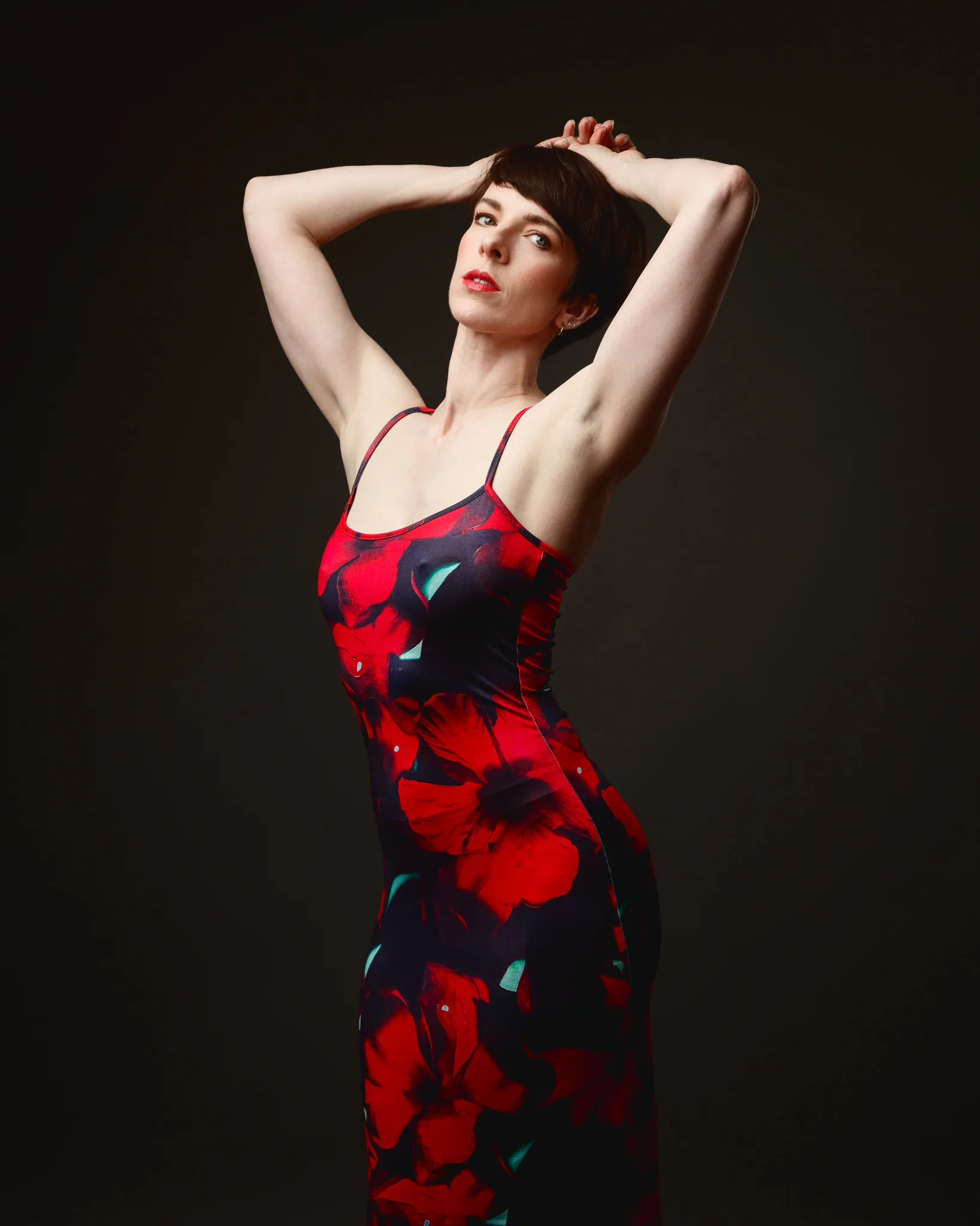 Woman in floral dress posing against dark background.