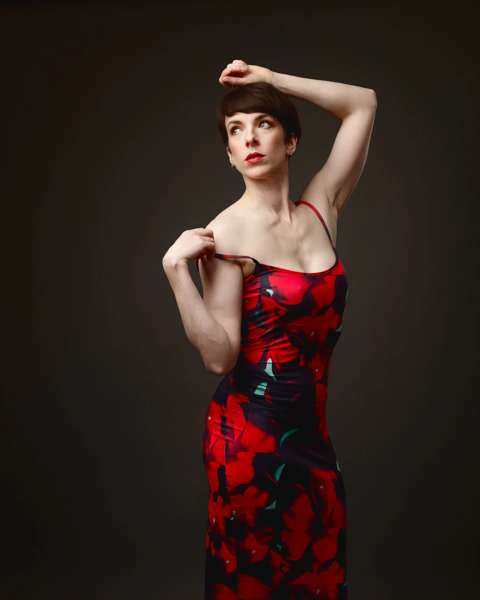 Woman in red floral dress posing elegantly.
