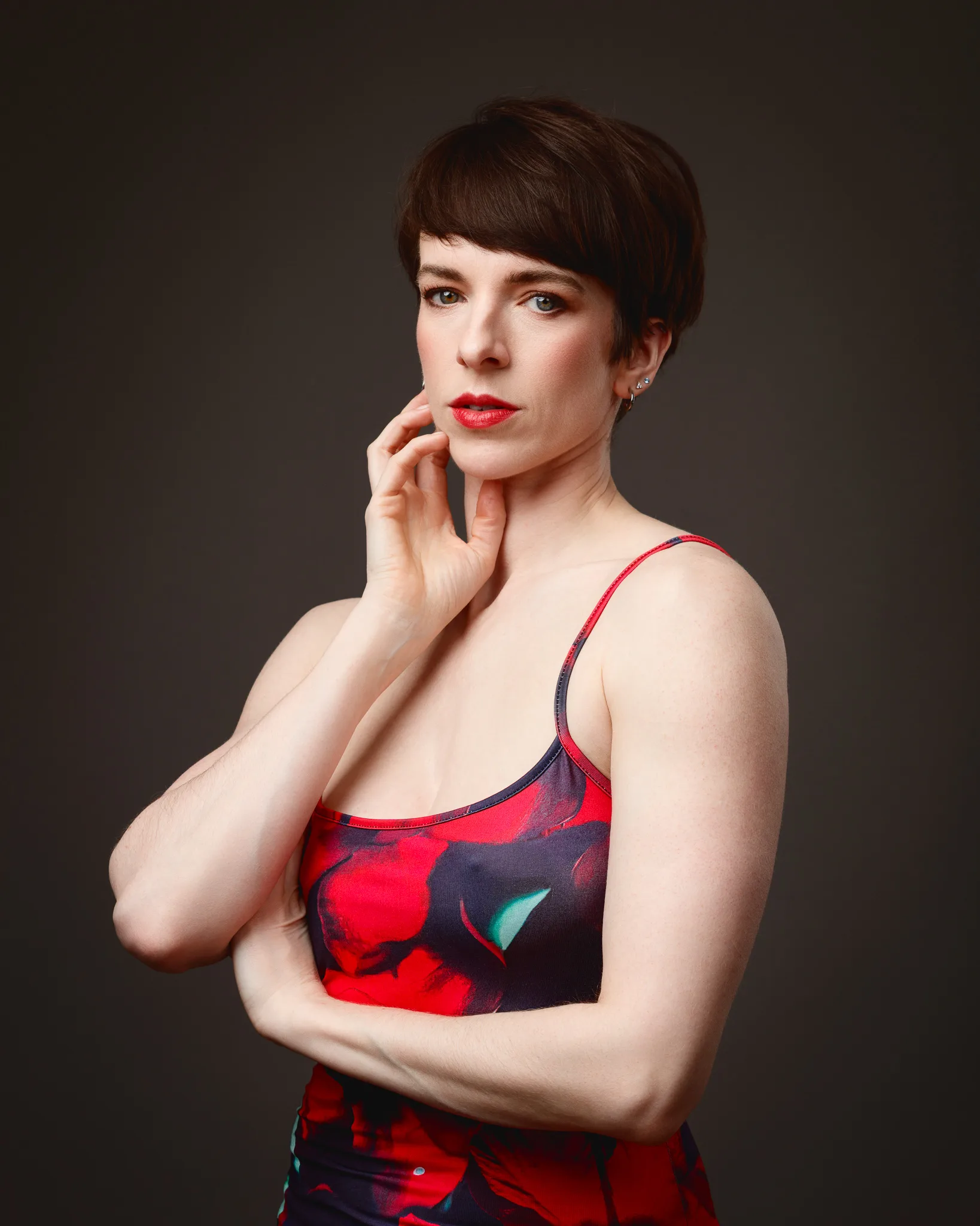 Person in floral dress posing against dark background.