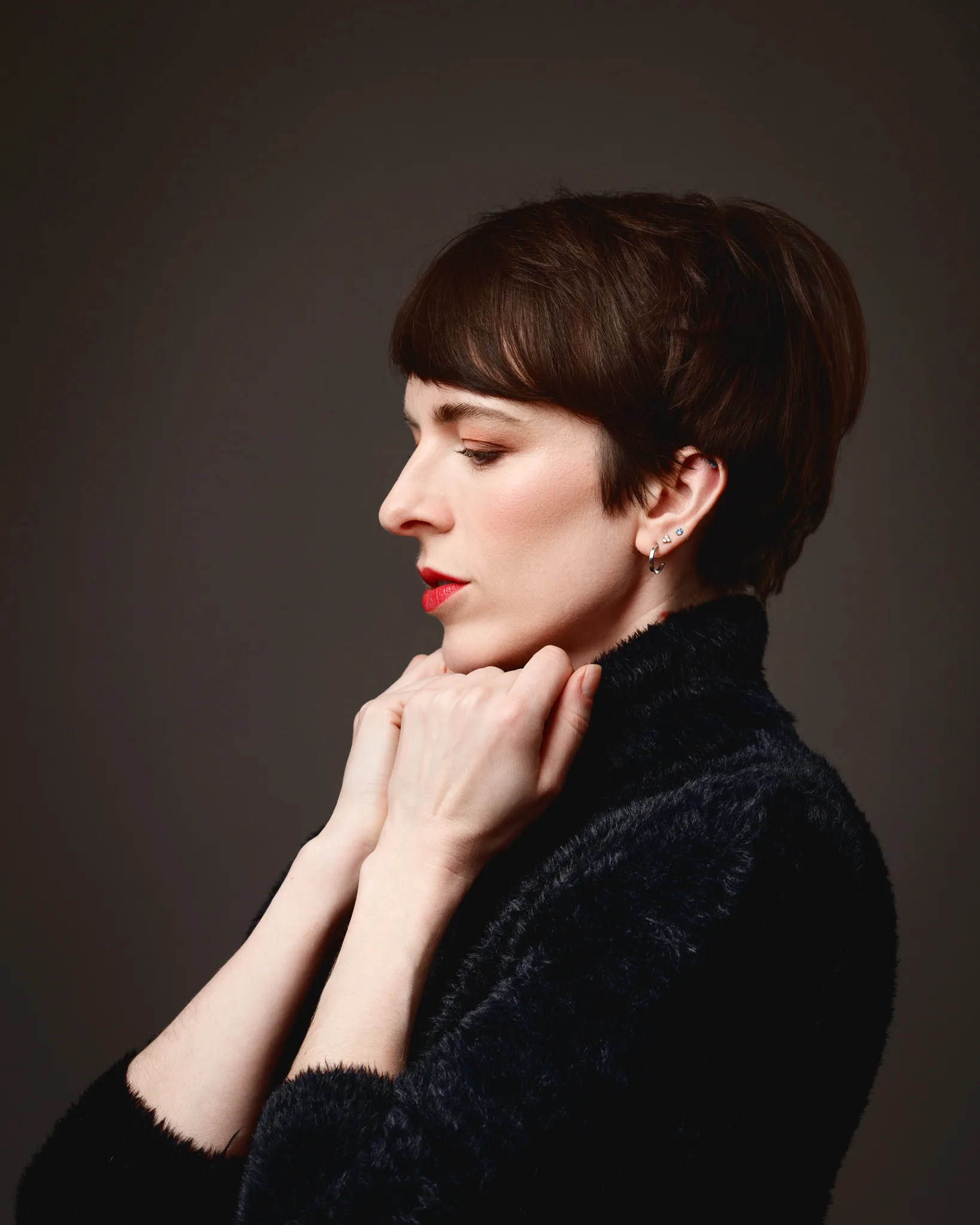 Woman in black jumper, profile view, thoughtful pose.