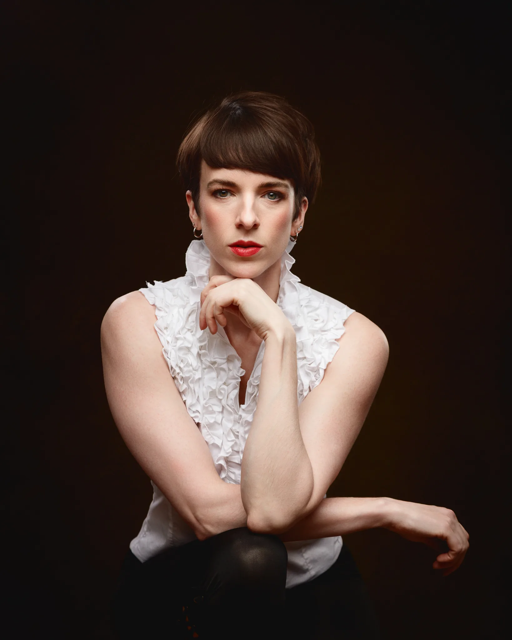 Portrait of person in white ruffled blouse.