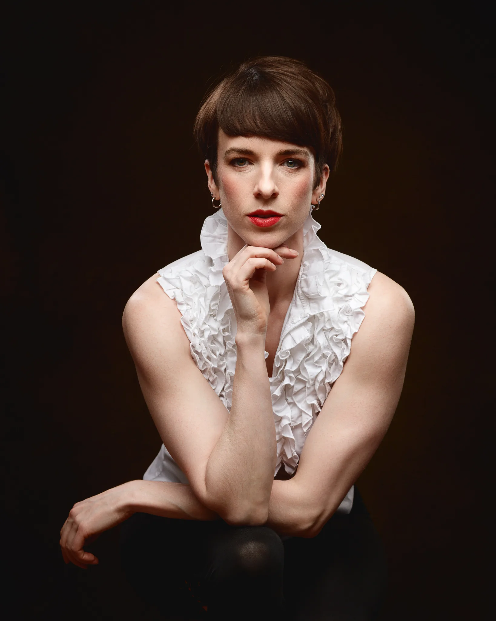 Person with short hair posing confidently in white top.