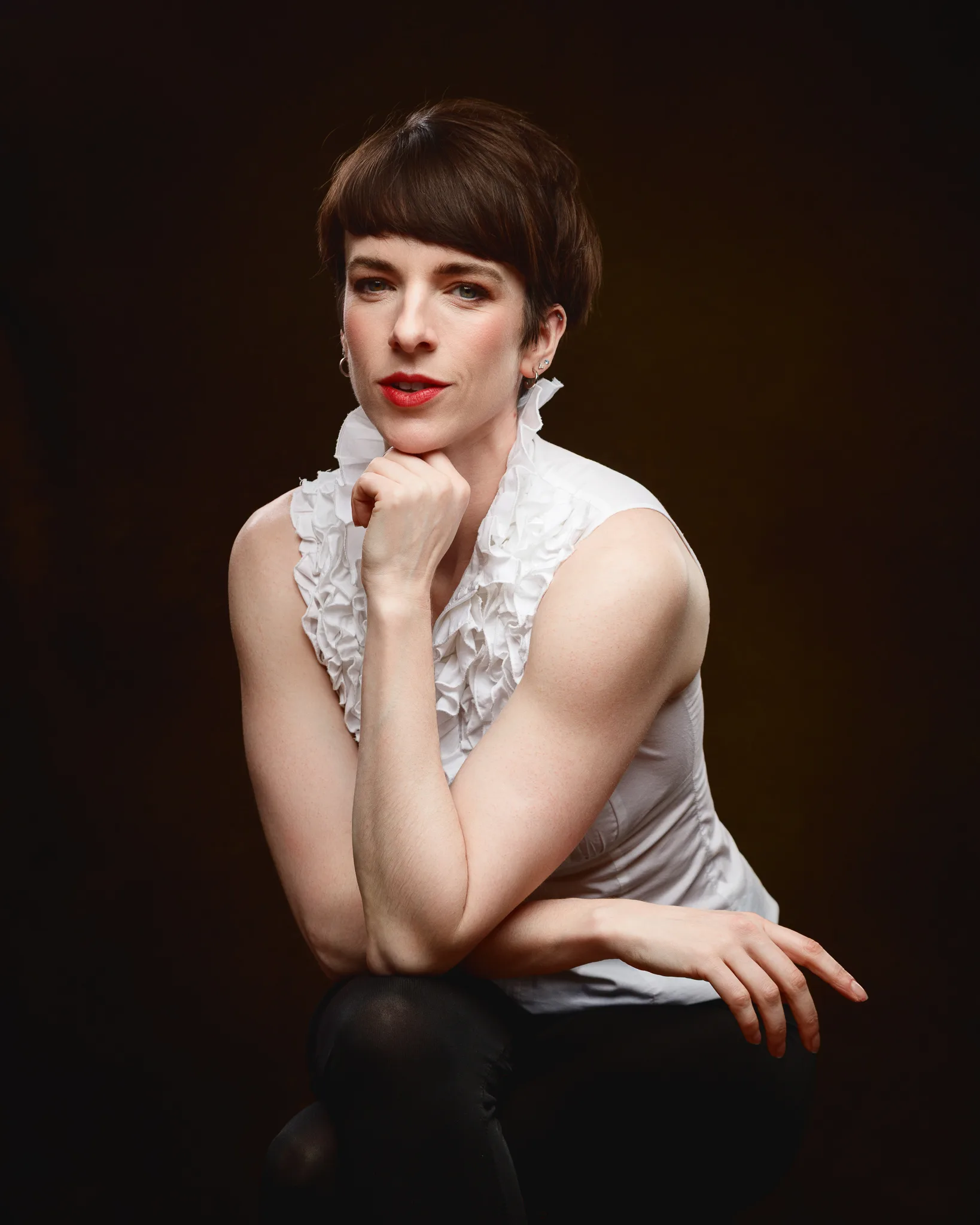 Person poses thoughtfully against dark background.