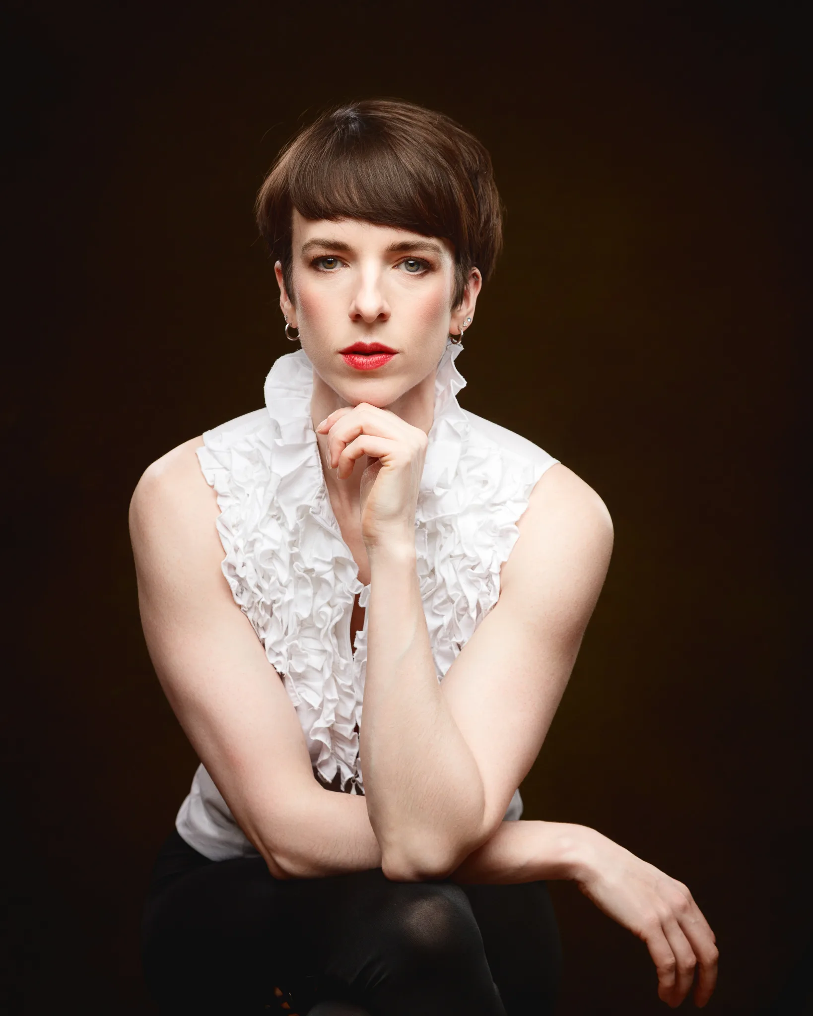 Woman in white ruffled blouse posing dramatically.