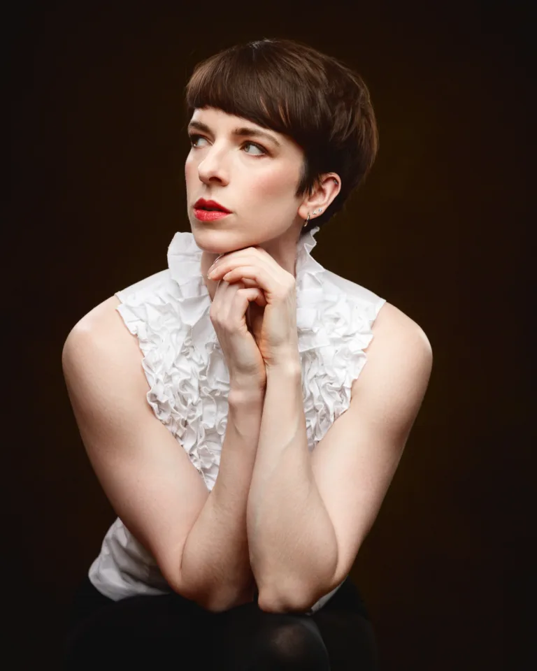 Person in white blouse posing thoughtfully.