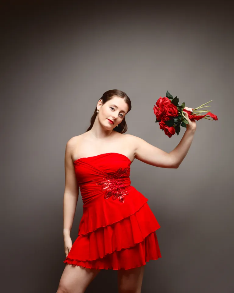 Woman in red dress holding red roses.