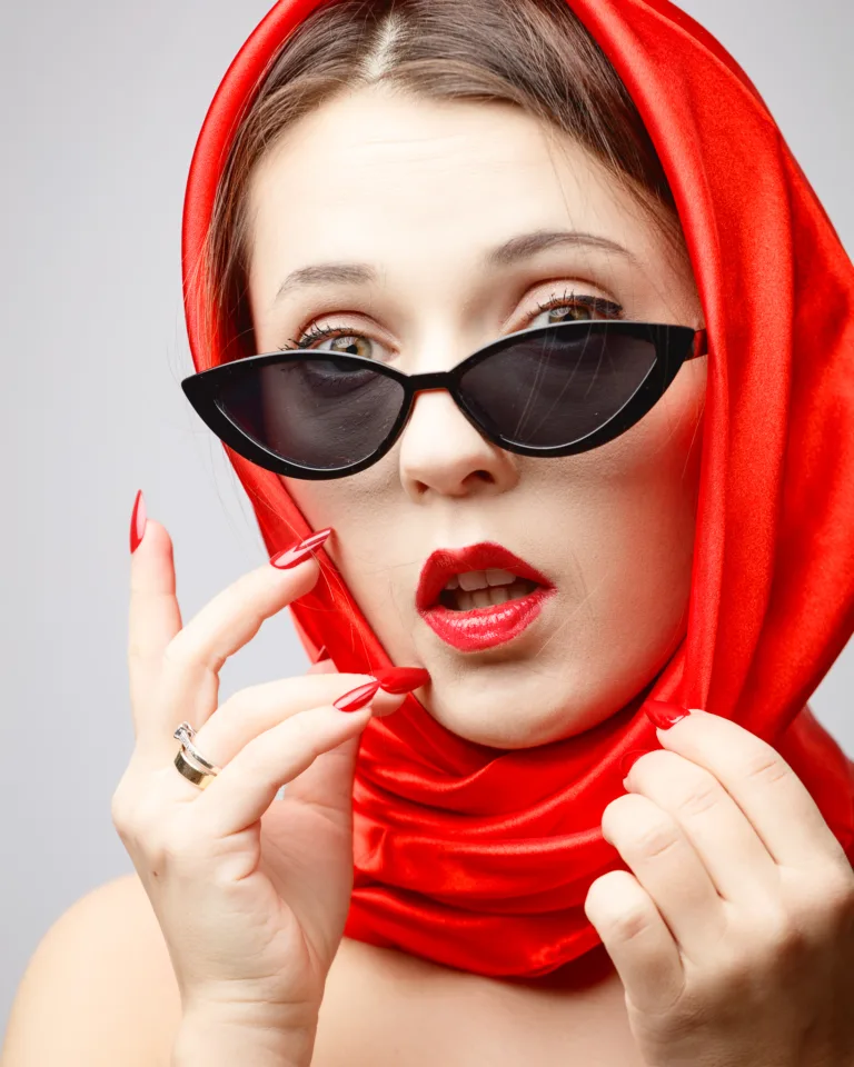 Woman wearing sunglasses and red scarf, stylish look.