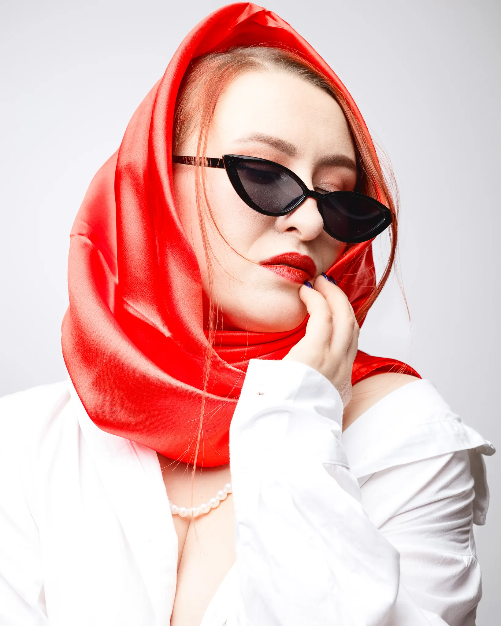 Woman posing with red scarf and sunglasses.