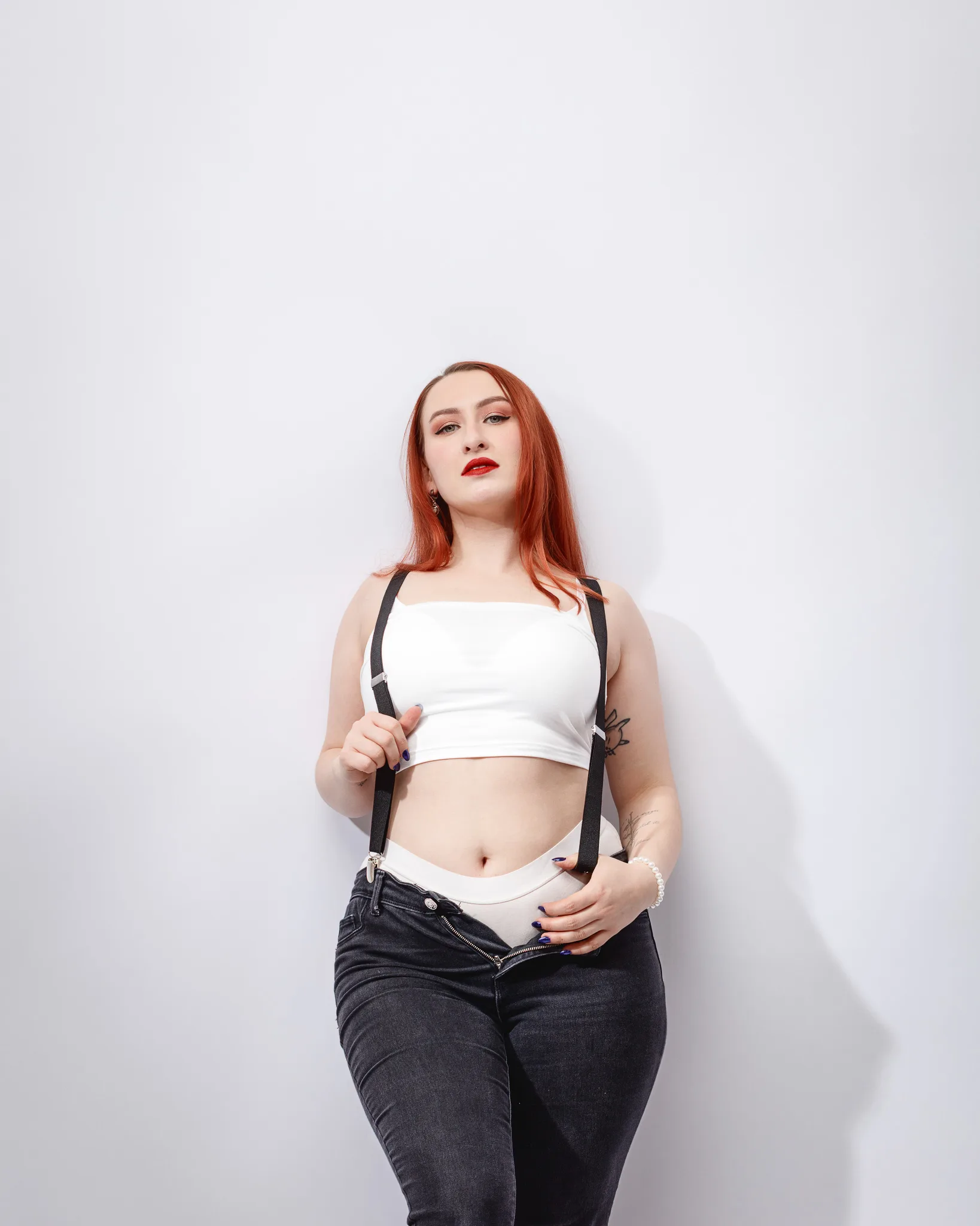 Fashionable woman in suspenders and jeans posing