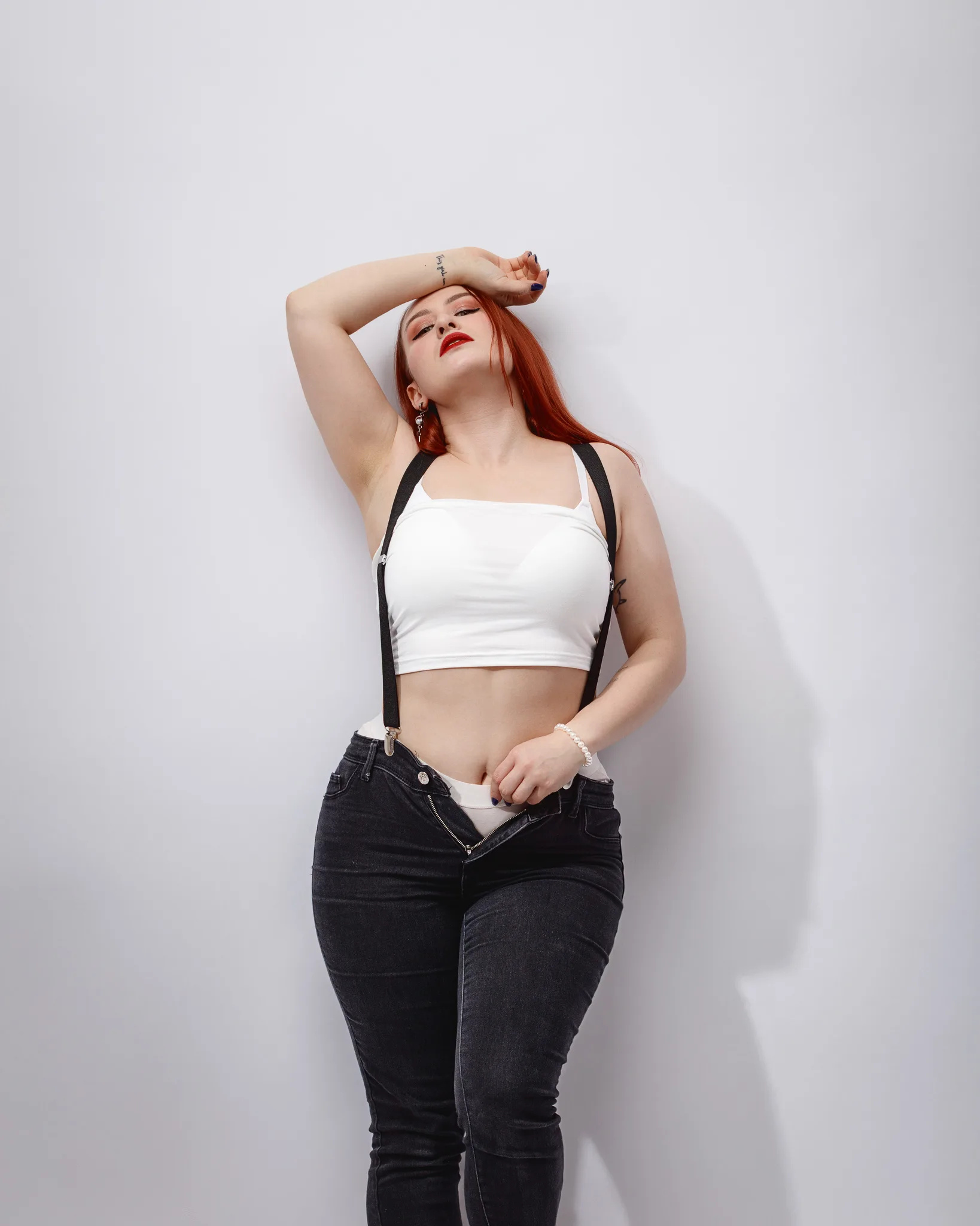 Woman posing in black jeans and white top.
