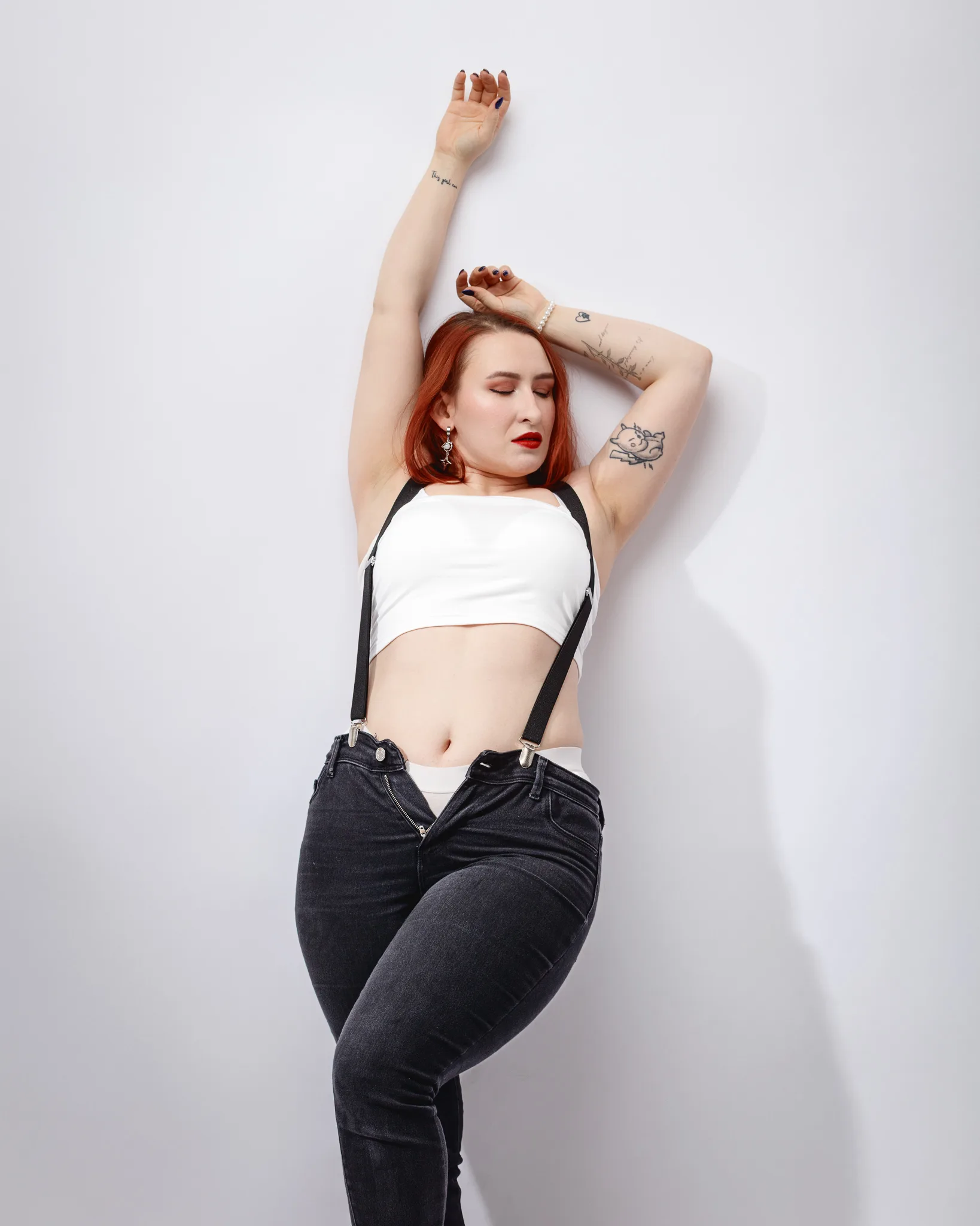 Person posing against white wall in stylish attire.