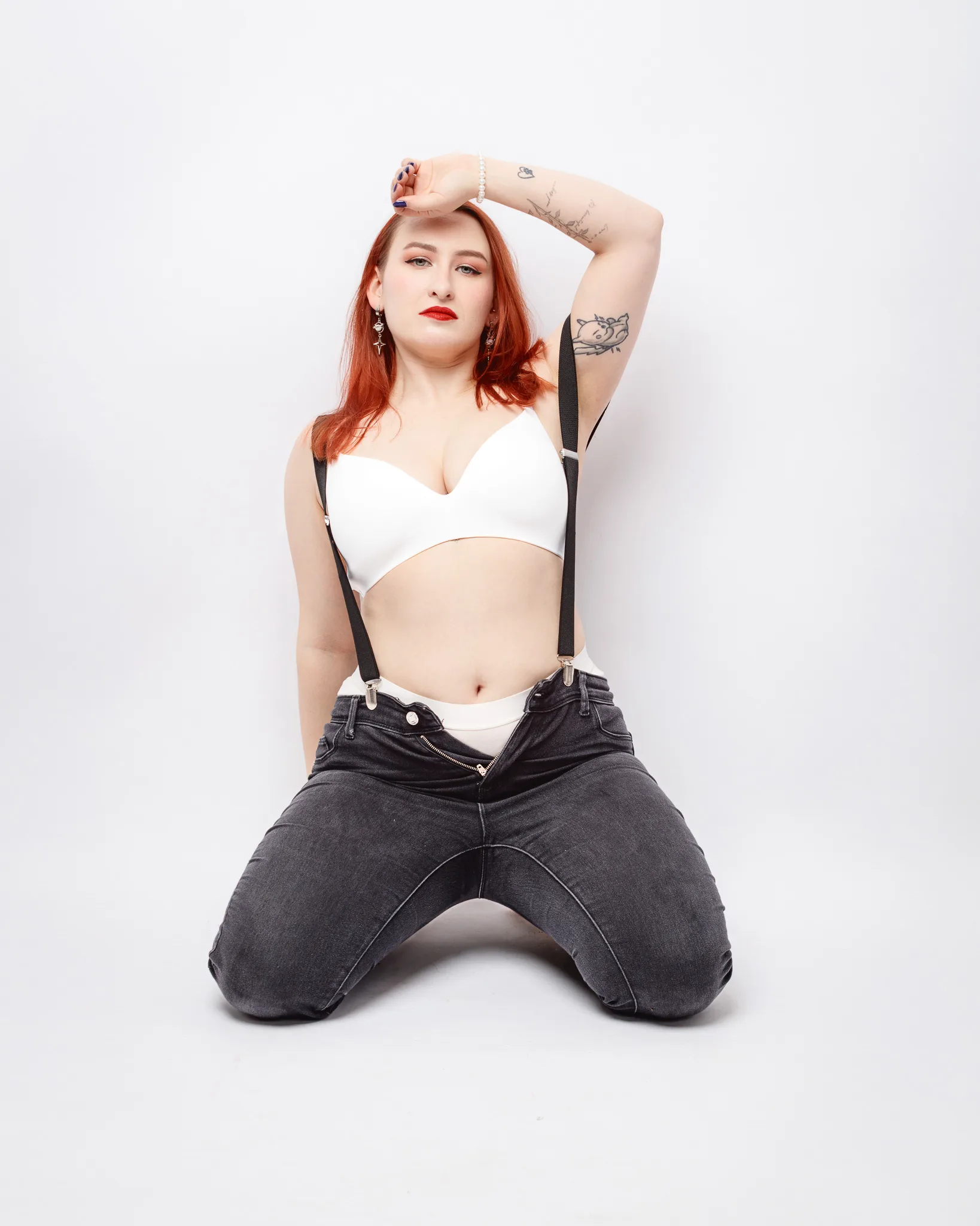 Model poses confidently in suspenders and white top.
