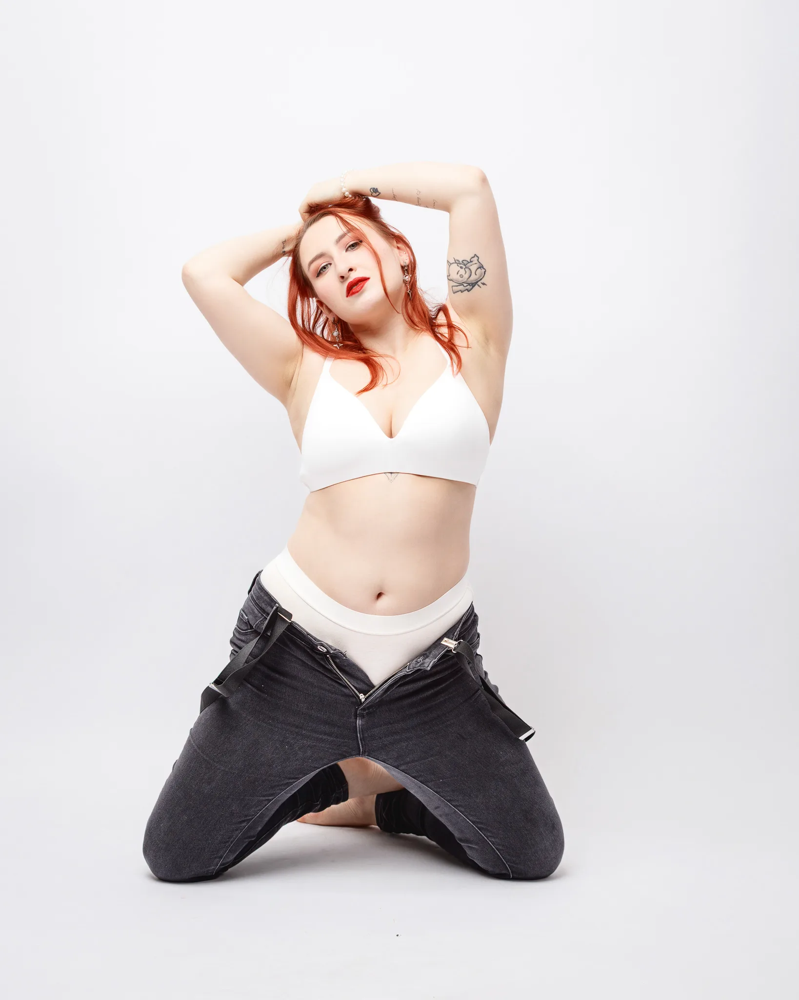Woman posing in white top and jeans.
