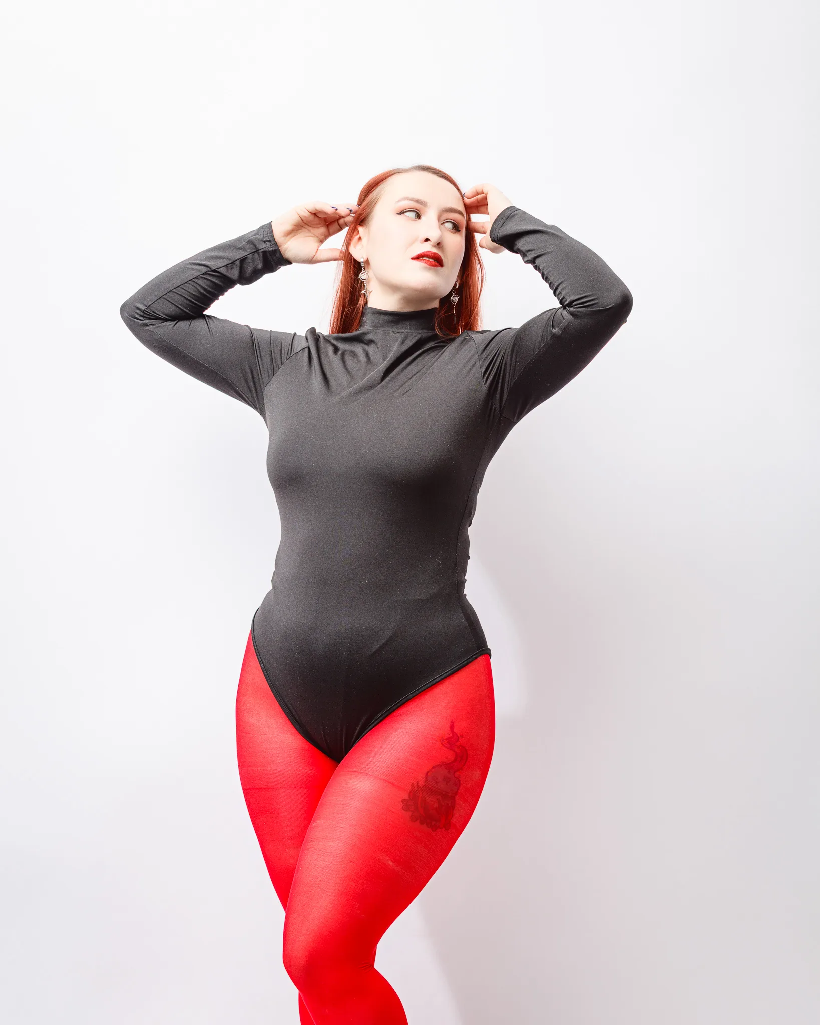 Person poses in black bodysuit and red tights.