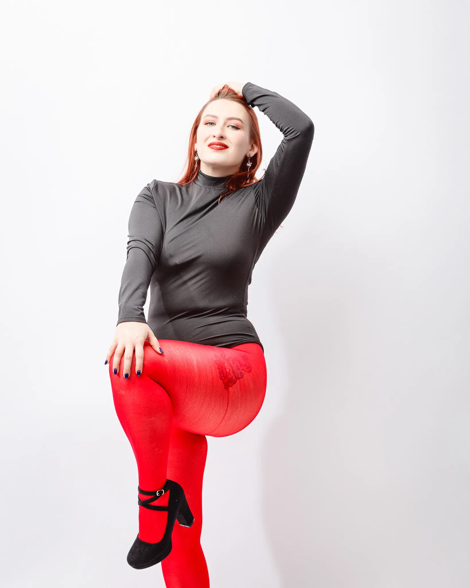 Person in grey top and red tights posing confidently.